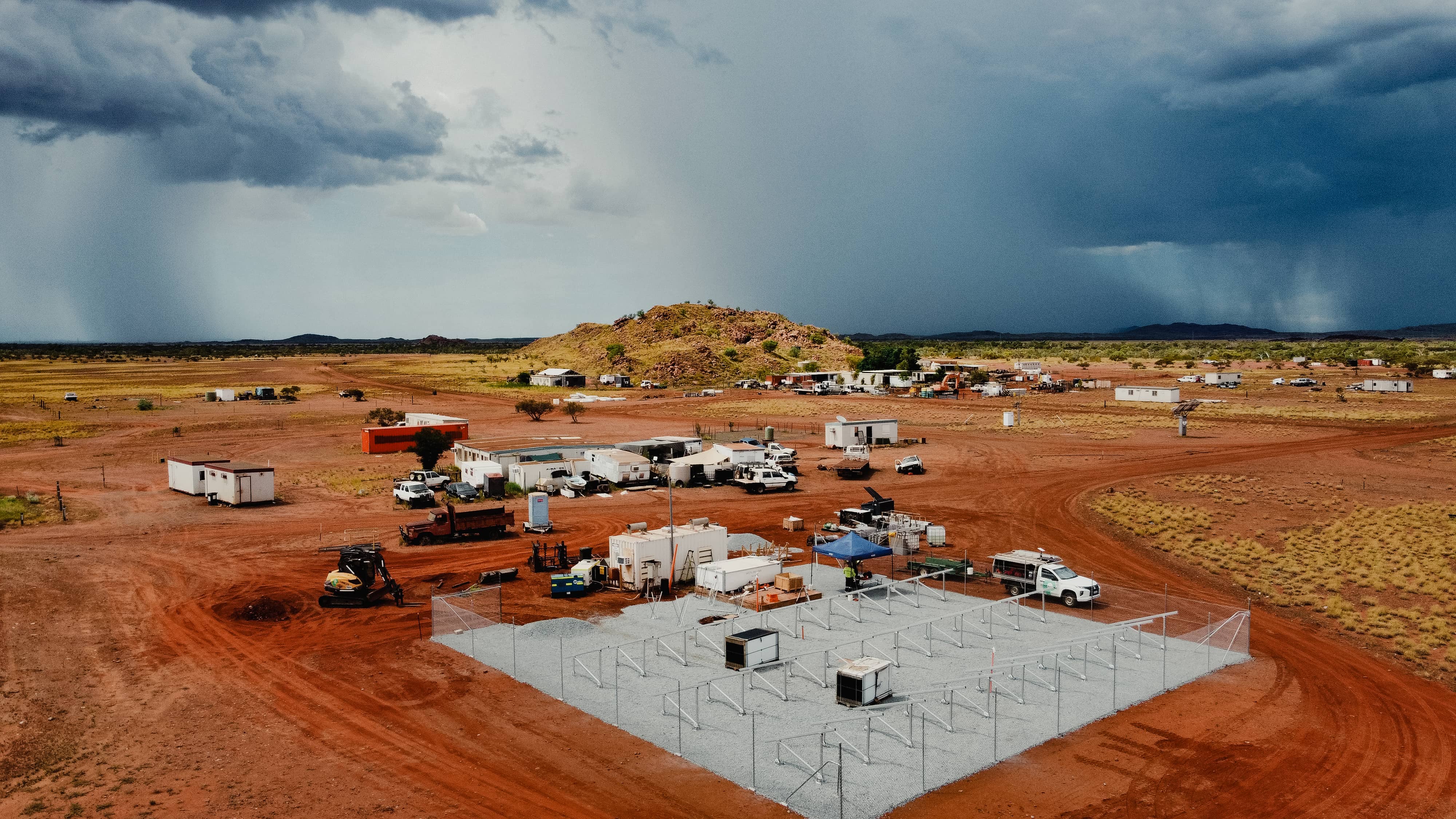 Remote construction site with infrastructure under stormy skies and active industrial activity.