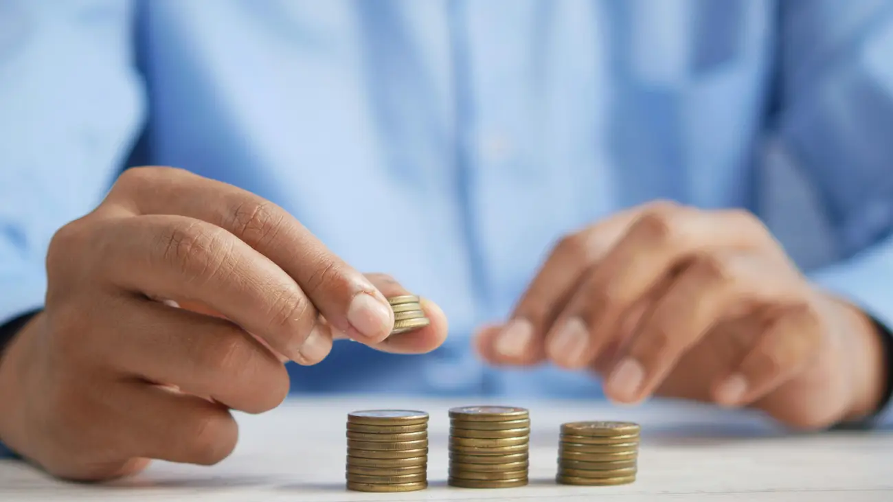 Hands stacking coins into organised piles, illustrating how charitable sports clubs can manage sponsorship income, use funds responsibly and protect their charitable status.