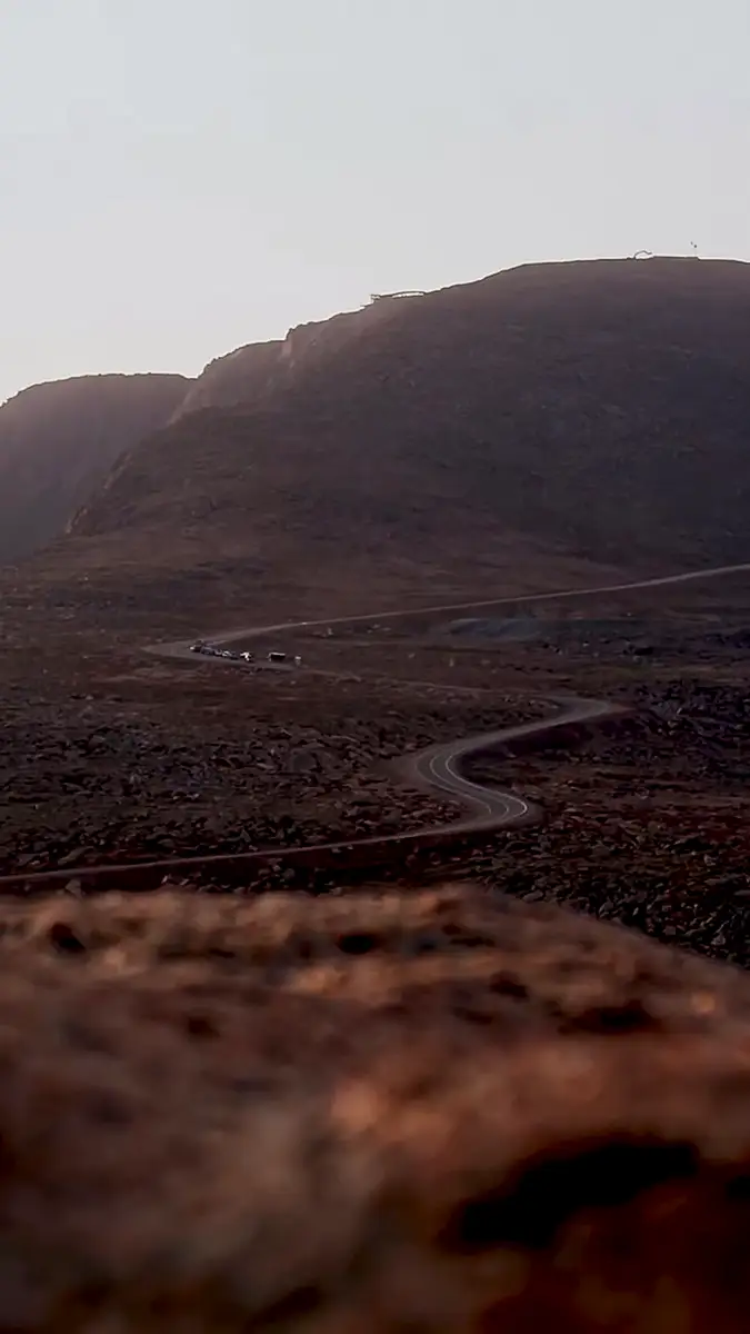 A desolate landscape with rolling brown hills and a winding path, under a muted sky.