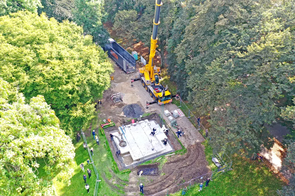 Isometrische Zeichnung eines Bauprojekts mit mehreren Gebäuden und markierten Strukturen in Rot
