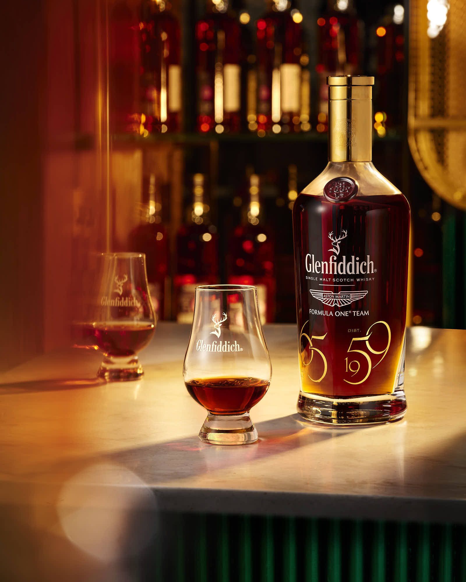 A bottle of whiskey with two glasses sits on a wooden surface, illuminated by warm, ambient lighting.