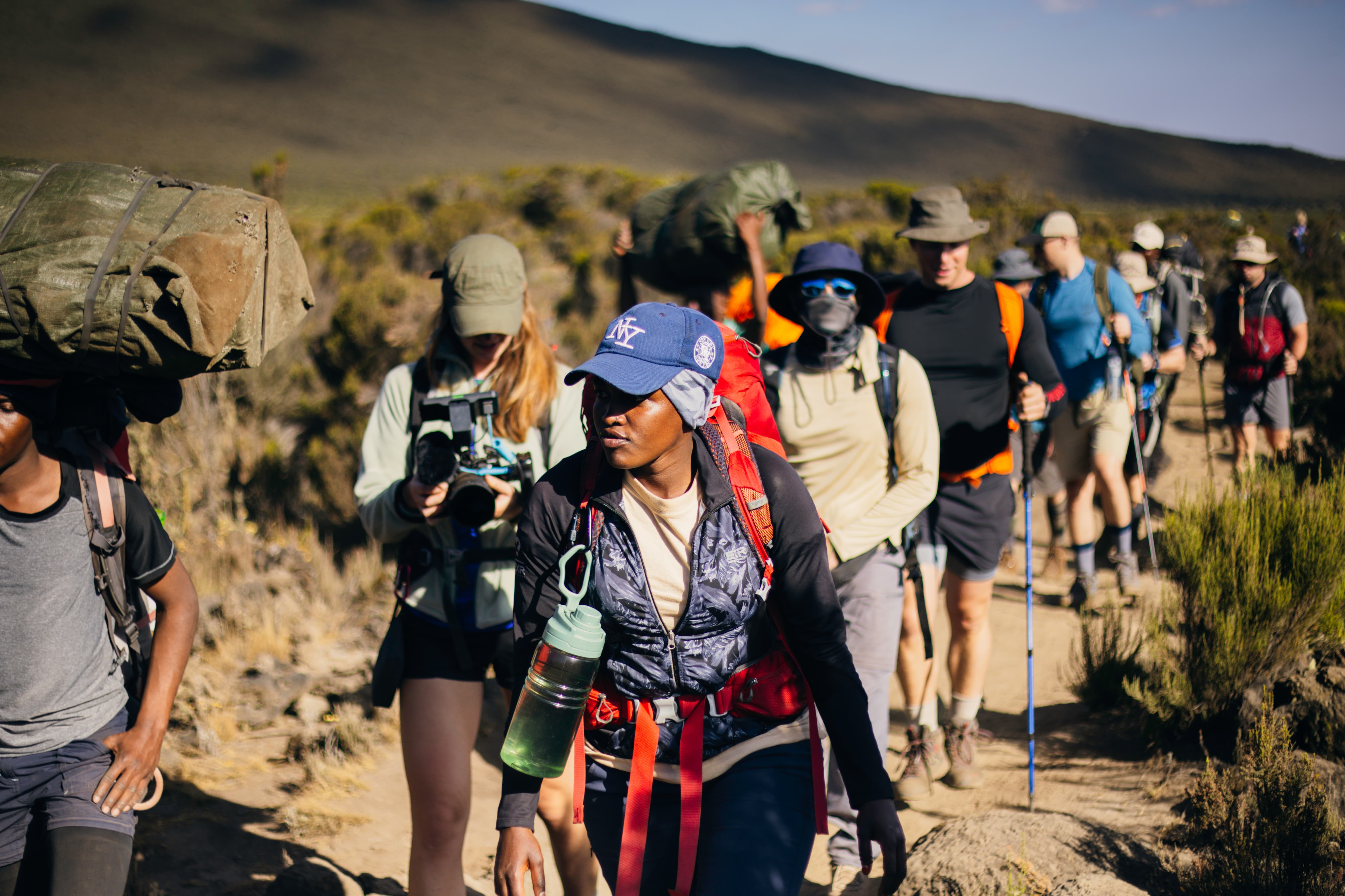 A first-time climber walking a marked trail on Kilimanjaro with a Legend Expeditions guide alongside.