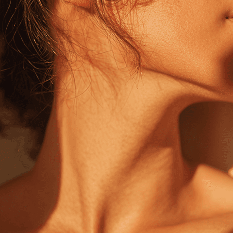 Close-up of a person’s neck and jawline in warm natural light, with soft shadows emphasizing skin texture and contours.
