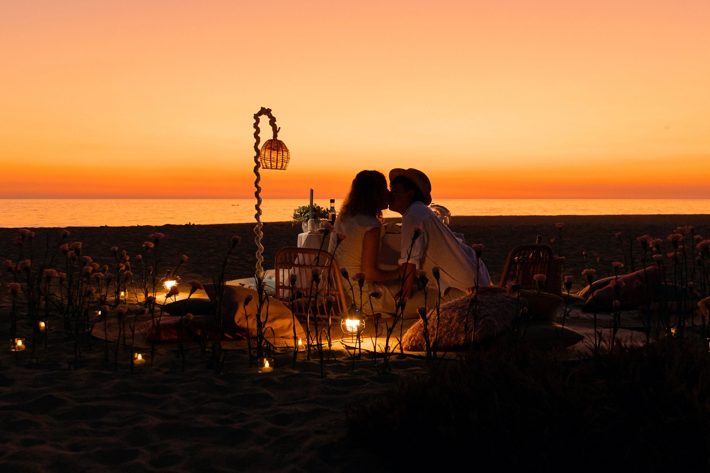 Momento de compromiso capturado durante una sesión fotográfica en la playa en el atardecer en un picnic