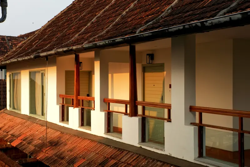 Exterior balcony corridor of Paddy Field View rooms at Vedic Village Alleppey with terracotta tiled roofs in warm evening light
