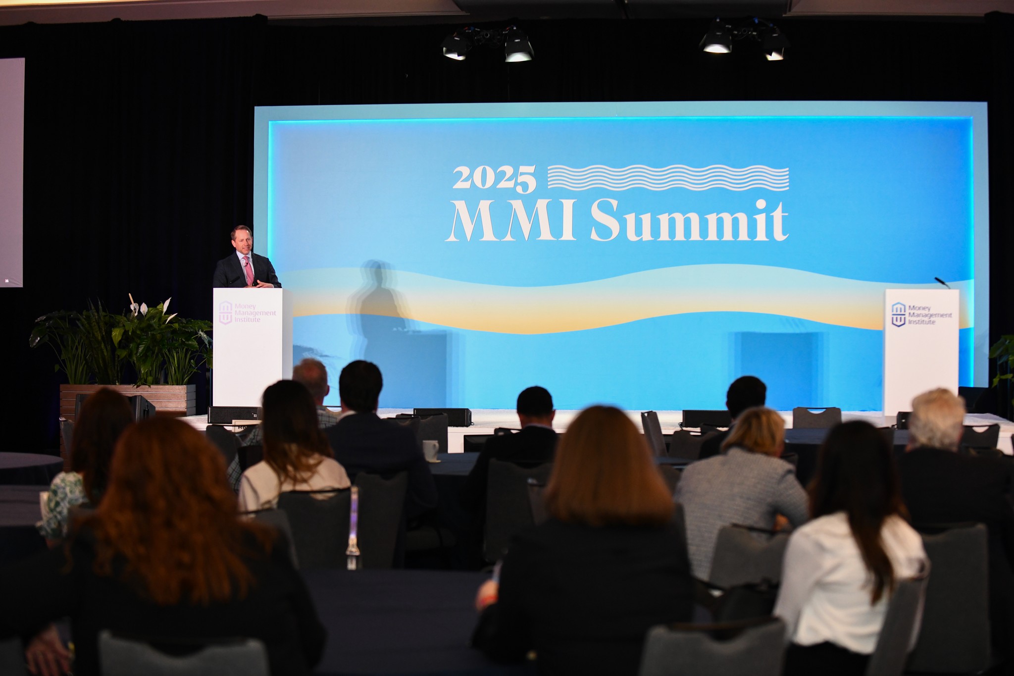 2025 MMI Summit wide view of stage with audience in foreground and one speaker at the right podium