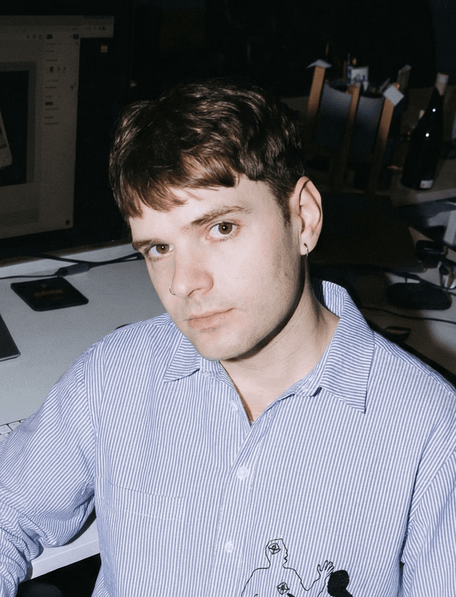 Haydon sitting at a desk in a blue and white striped collar shirt.