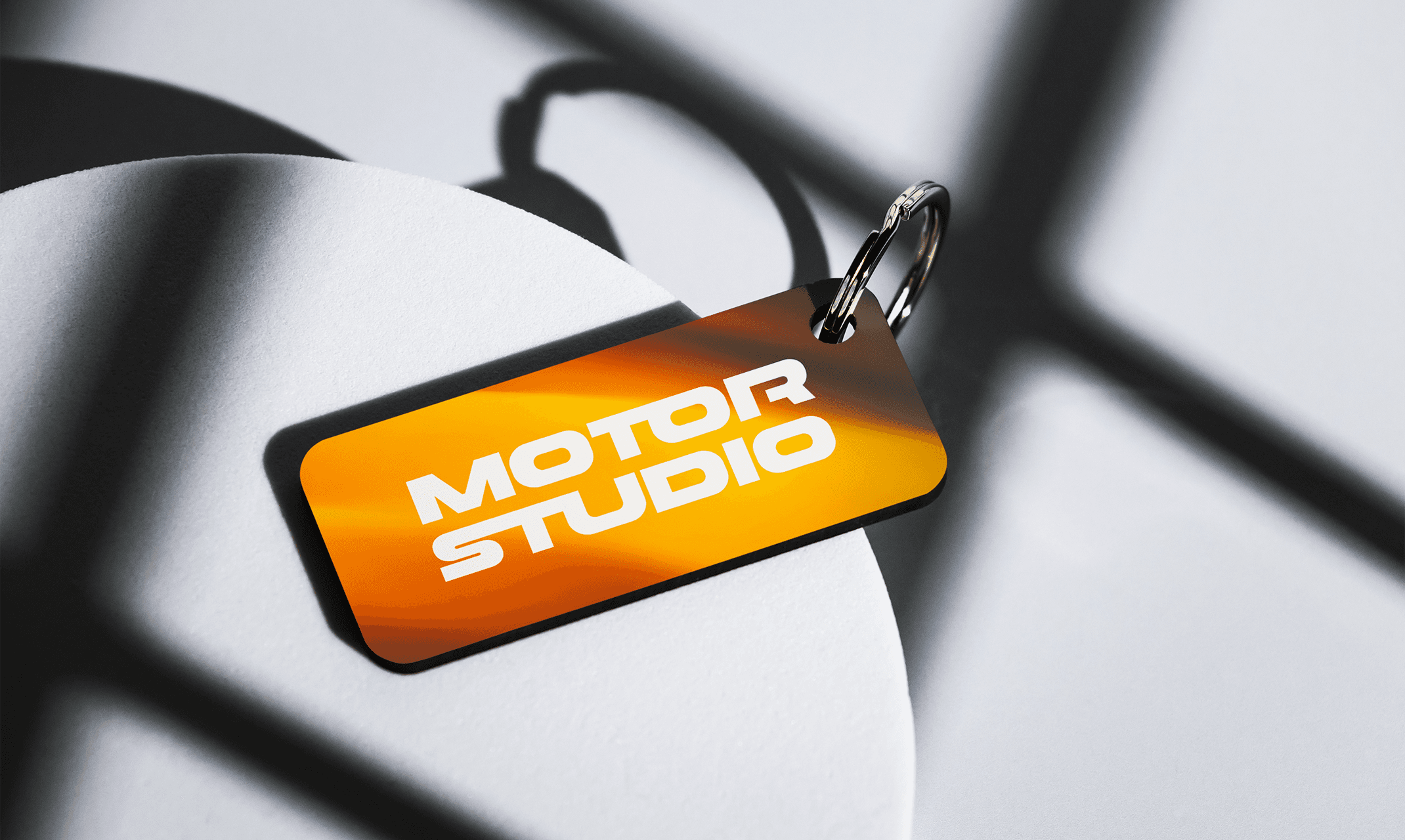 Porte-clés Motor Studio avec logo sur fond orange, élément de branding pour une concession automobile.
