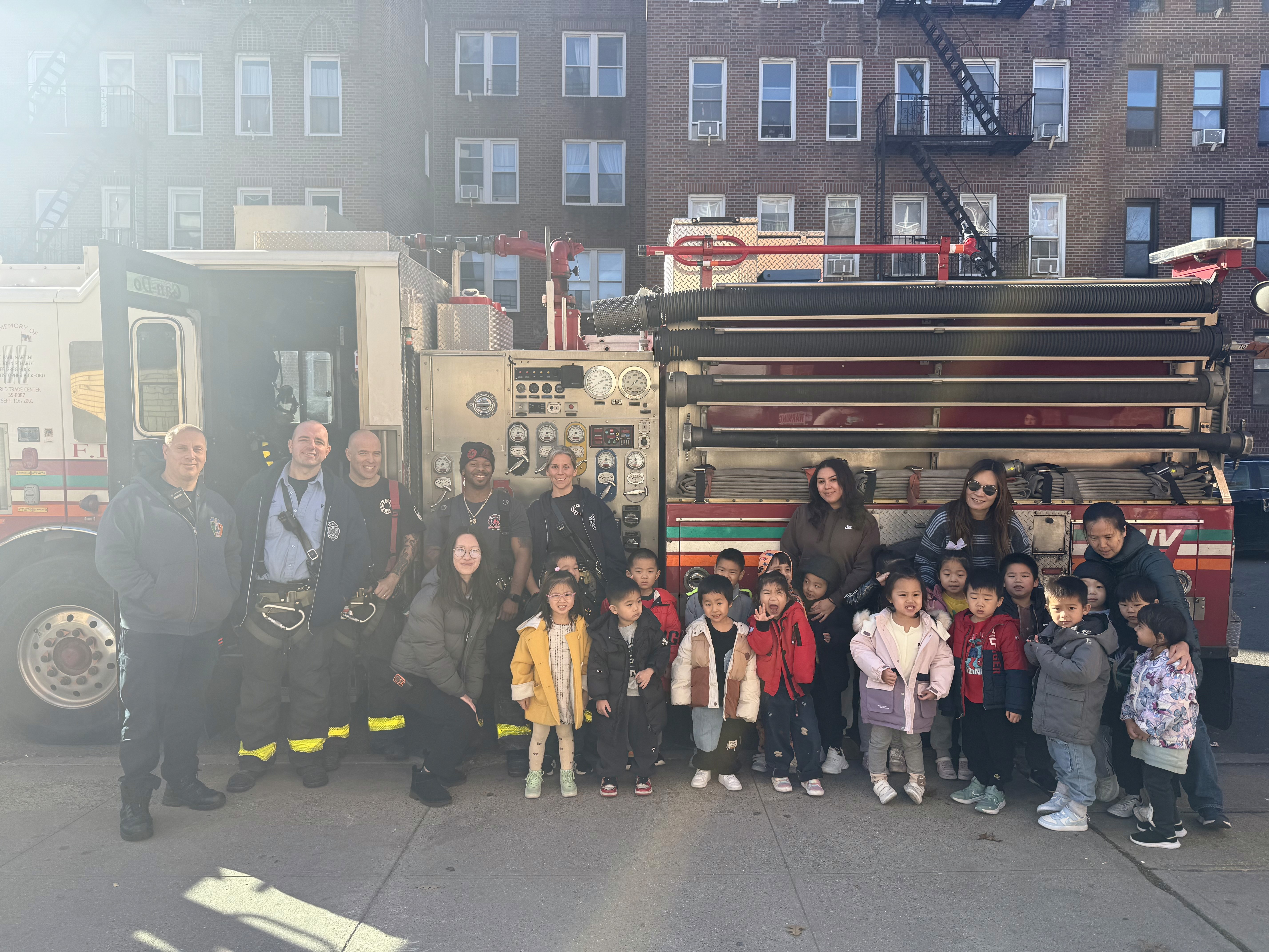 A group of young students and their teachers pose near a fire truck with their local fire department.