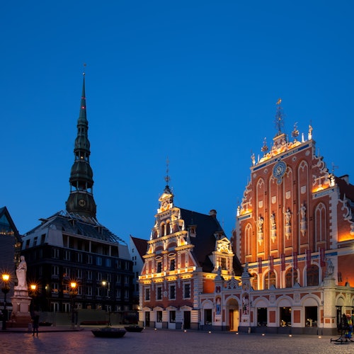 在黄昏时分，这座历史悠久的广场展现出灯火辉煌的哥特式建筑，与湛蓝的天空相映成趣，修长的尖塔高耸入云。