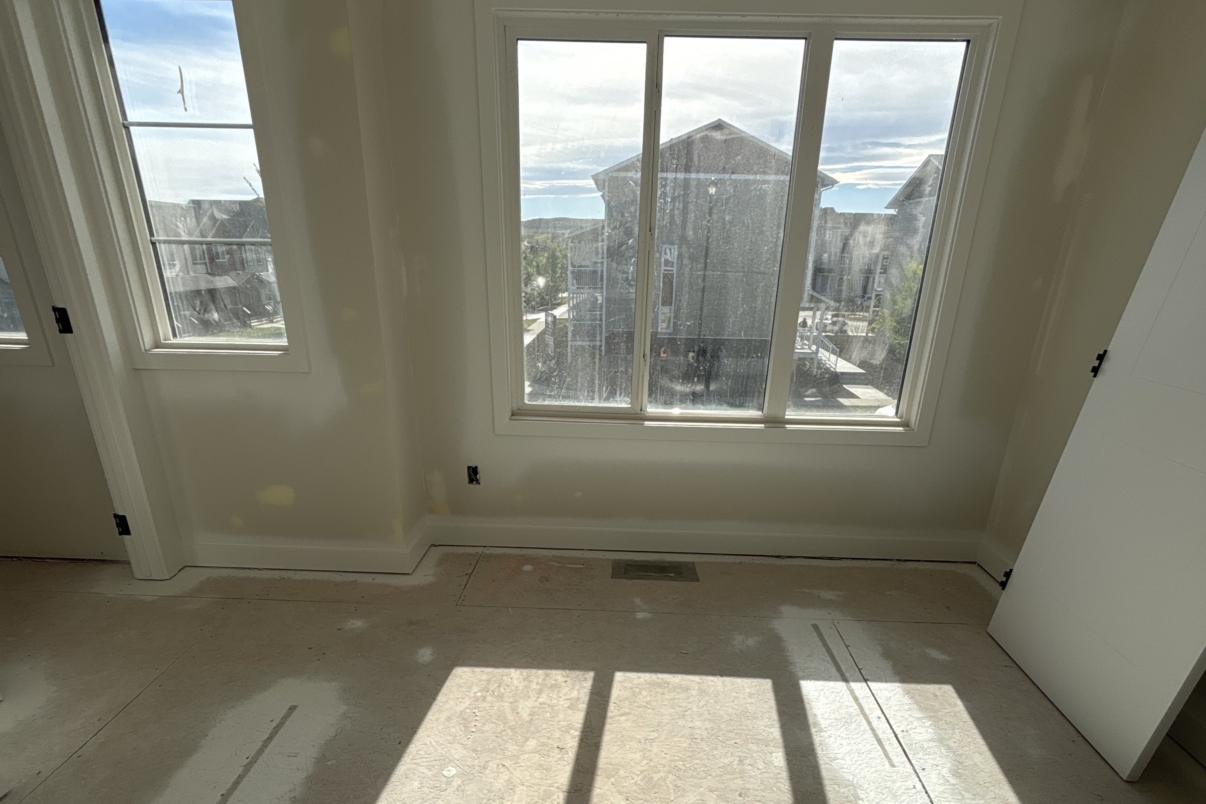 Heartland primary bedroom during construction: bare walls and subfloor in afternoon light