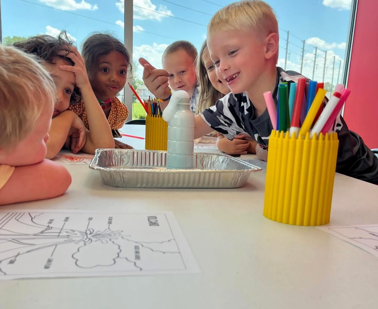Excited kids sitting at table, looking at a science experiment