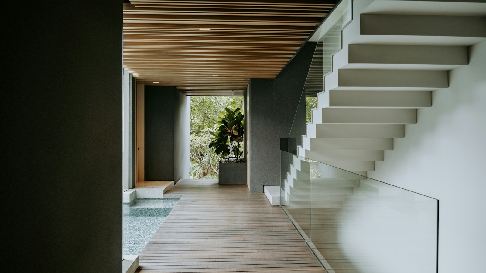 A long hallway with a wooden floor and stairs