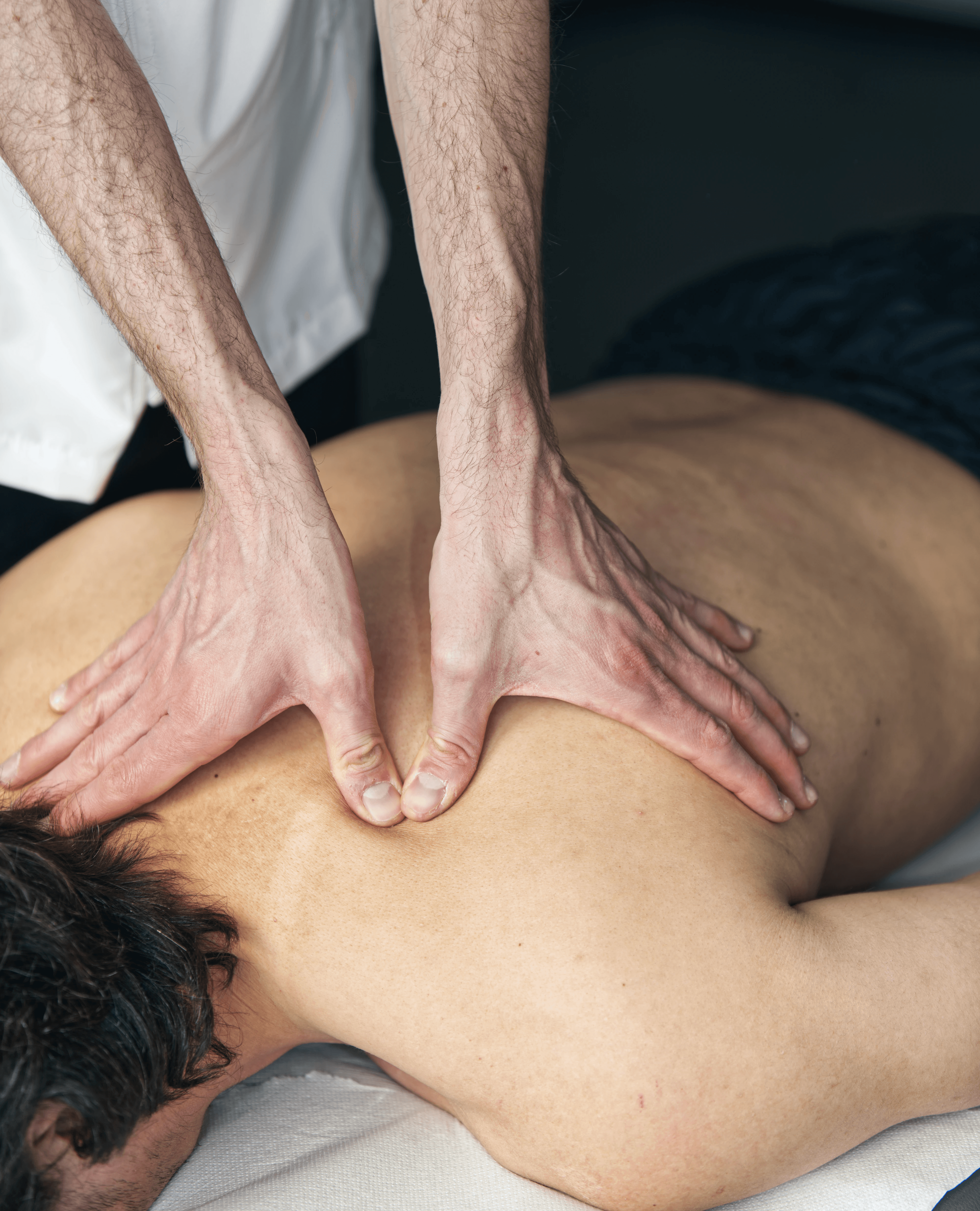 A man and woman sit on beige chairs in a modern room with a red paneled wall. A red pendant light hangs above a wooden coffee table between them.