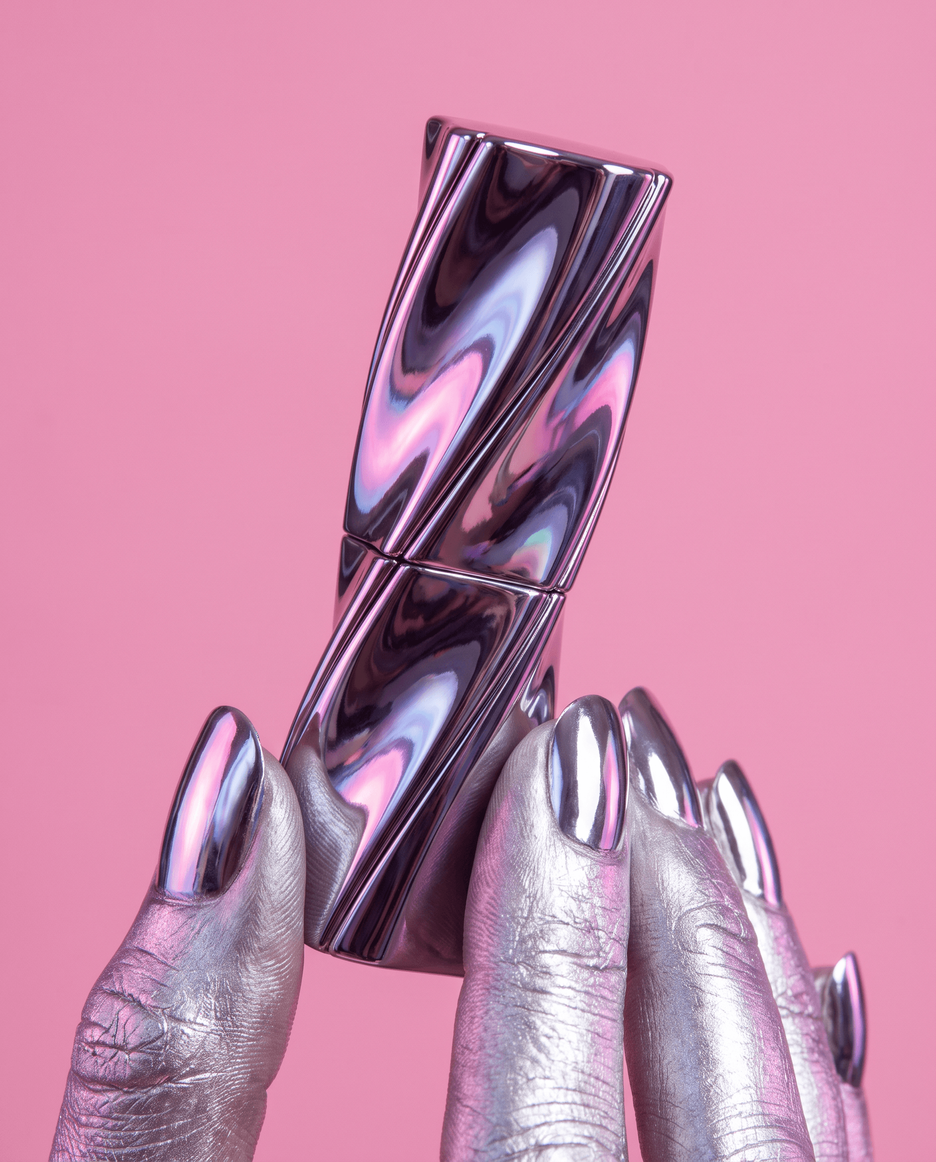 Silver-painted hand with chrome nails holding a swirled metallic lipstick on pink
