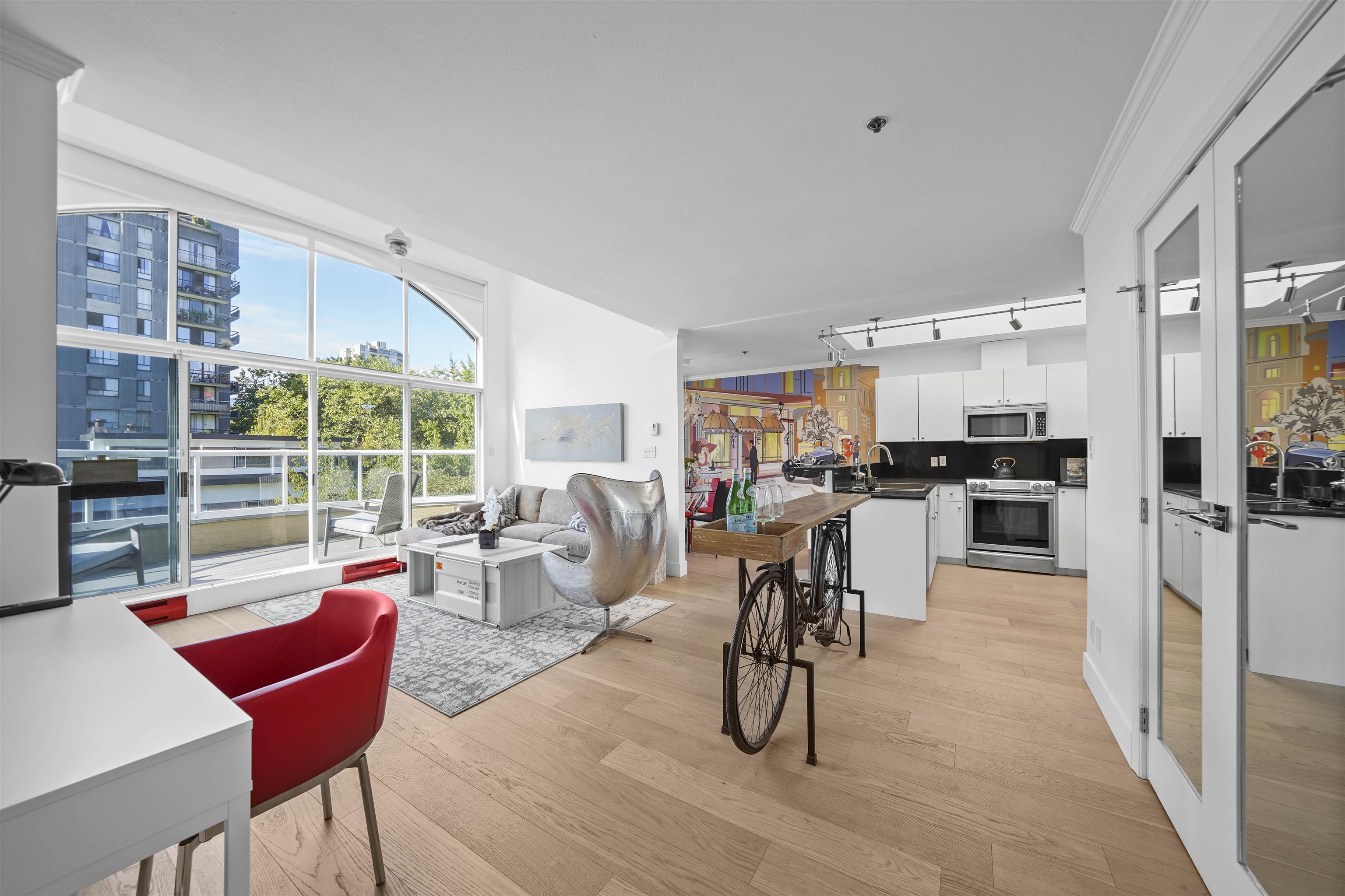 Bright, modern open-concept living space with large windows, outdoor seating, and stylish decor.