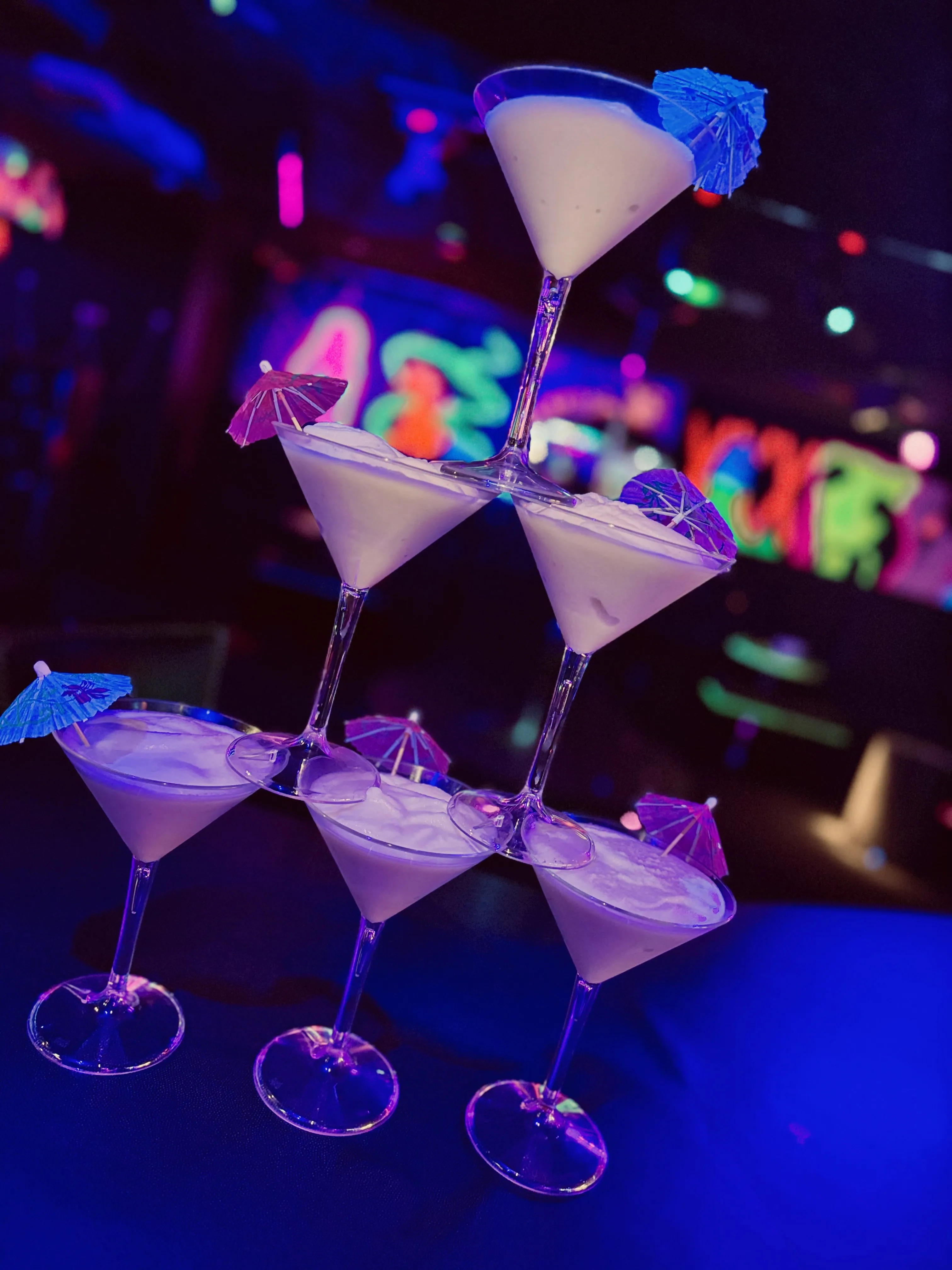 Cocktails in martini glasses under colourful nightclub lights