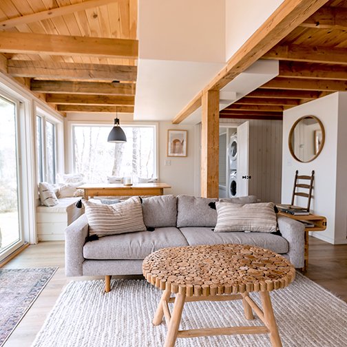 A living room with exposed beams, a grey sofa and large windows