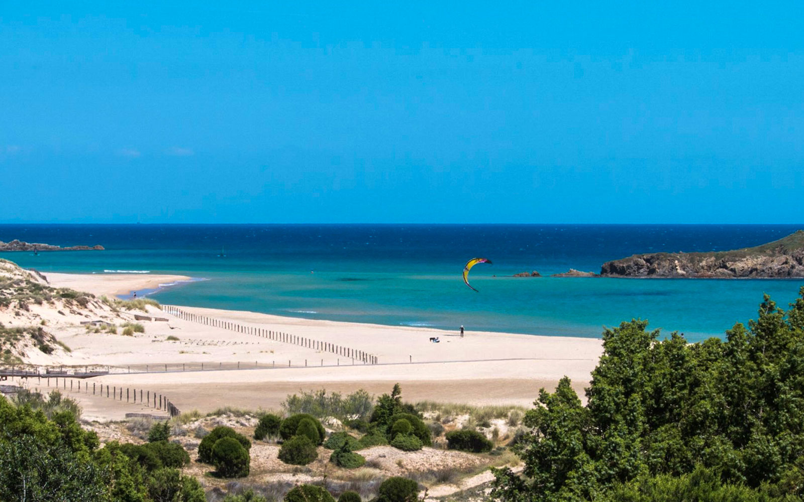 Chia beach with kite surfer and mountains in Cagliari, Sardinia.