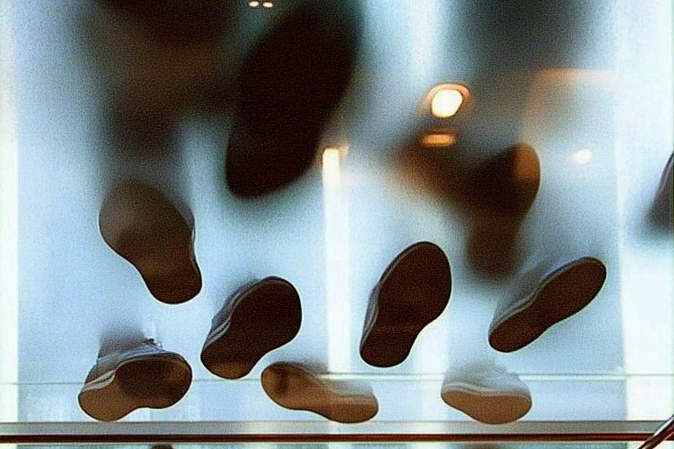 A glass floor with shoe soles pressed against it from below. The abstract, dreamlike atmosphere symbolizes participative strategizing, highlighting the importance of diverse perspectives in strategy routines