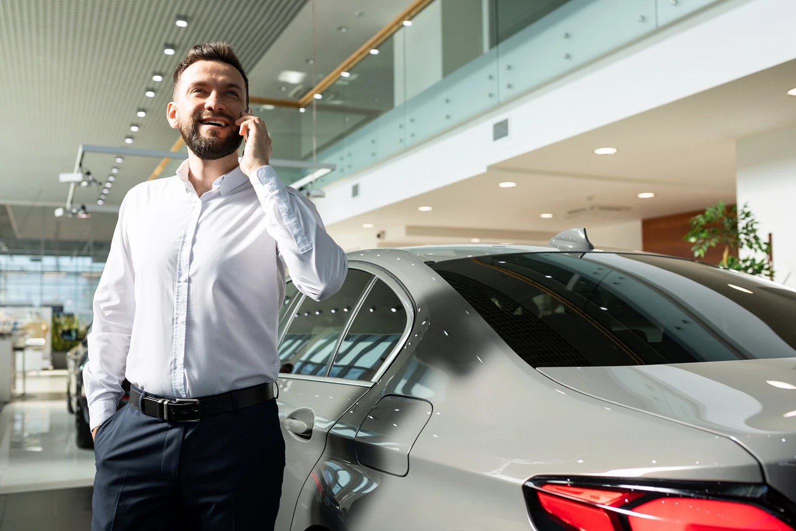 a man in a car dealership talking on the phone well