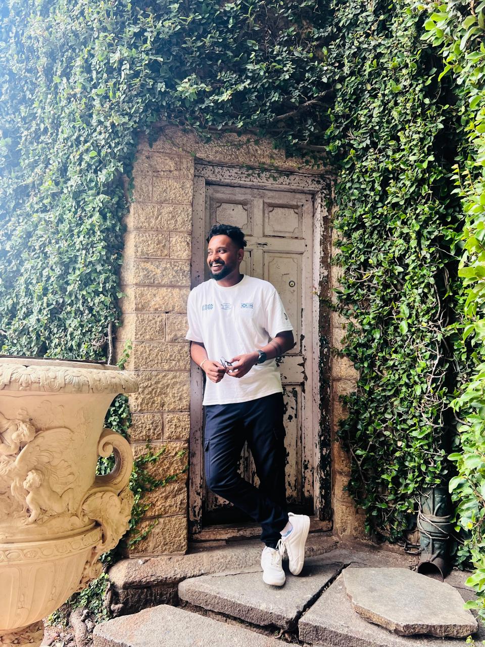 Black-and-white portrait of a Black person in a suit looking upward, shadow on white backdrop.