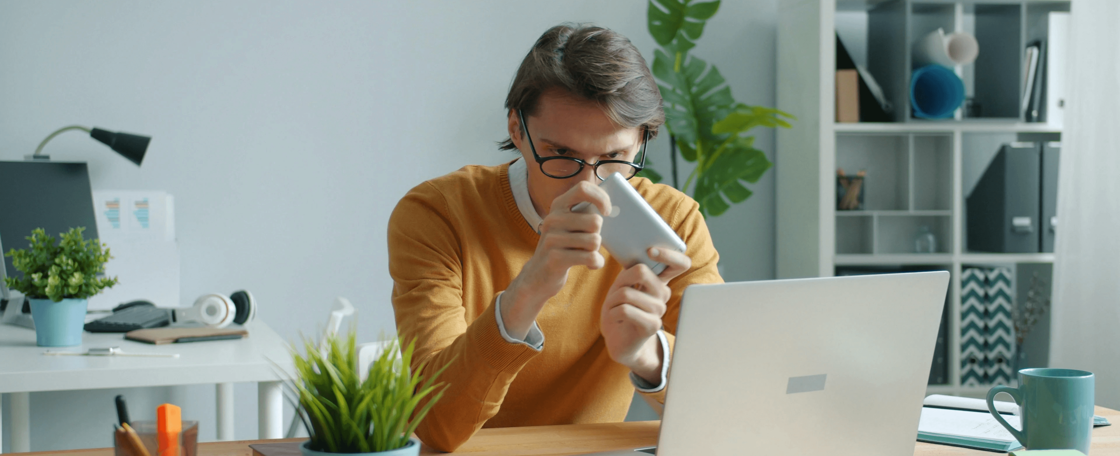 Man in yellow sweater drinking from mug at desk