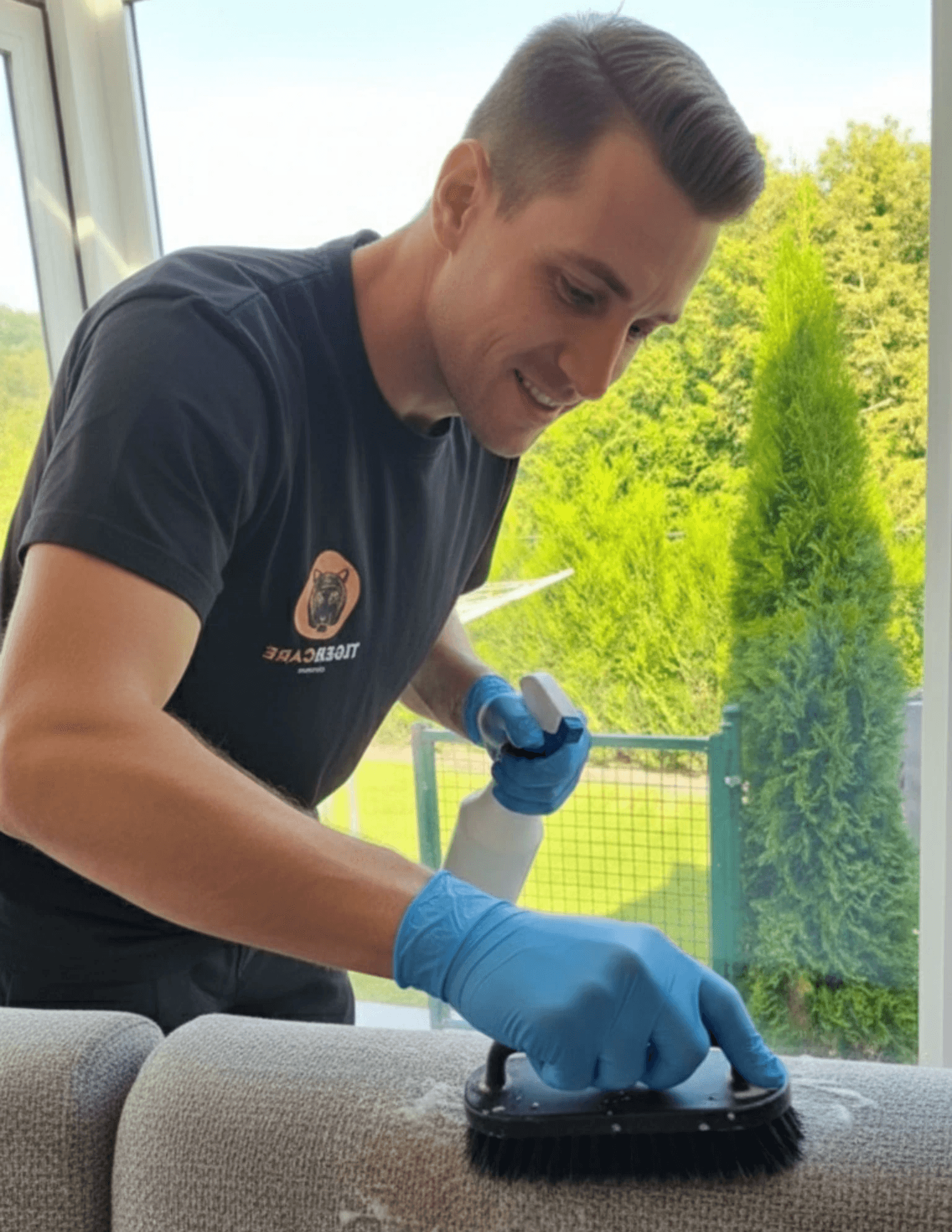 A person wearing bright green gloves is cleaning a surface with a cloth and a spray bottle.