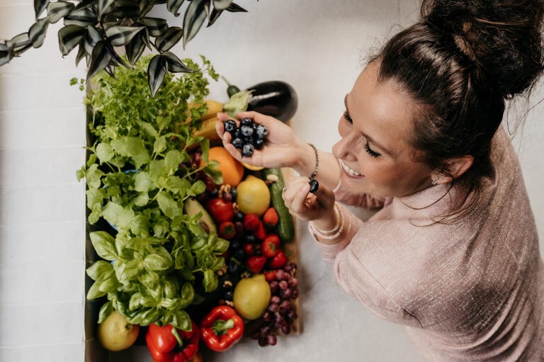 A woman arranging colorful fruits and vegetables on a table, focused on her task.