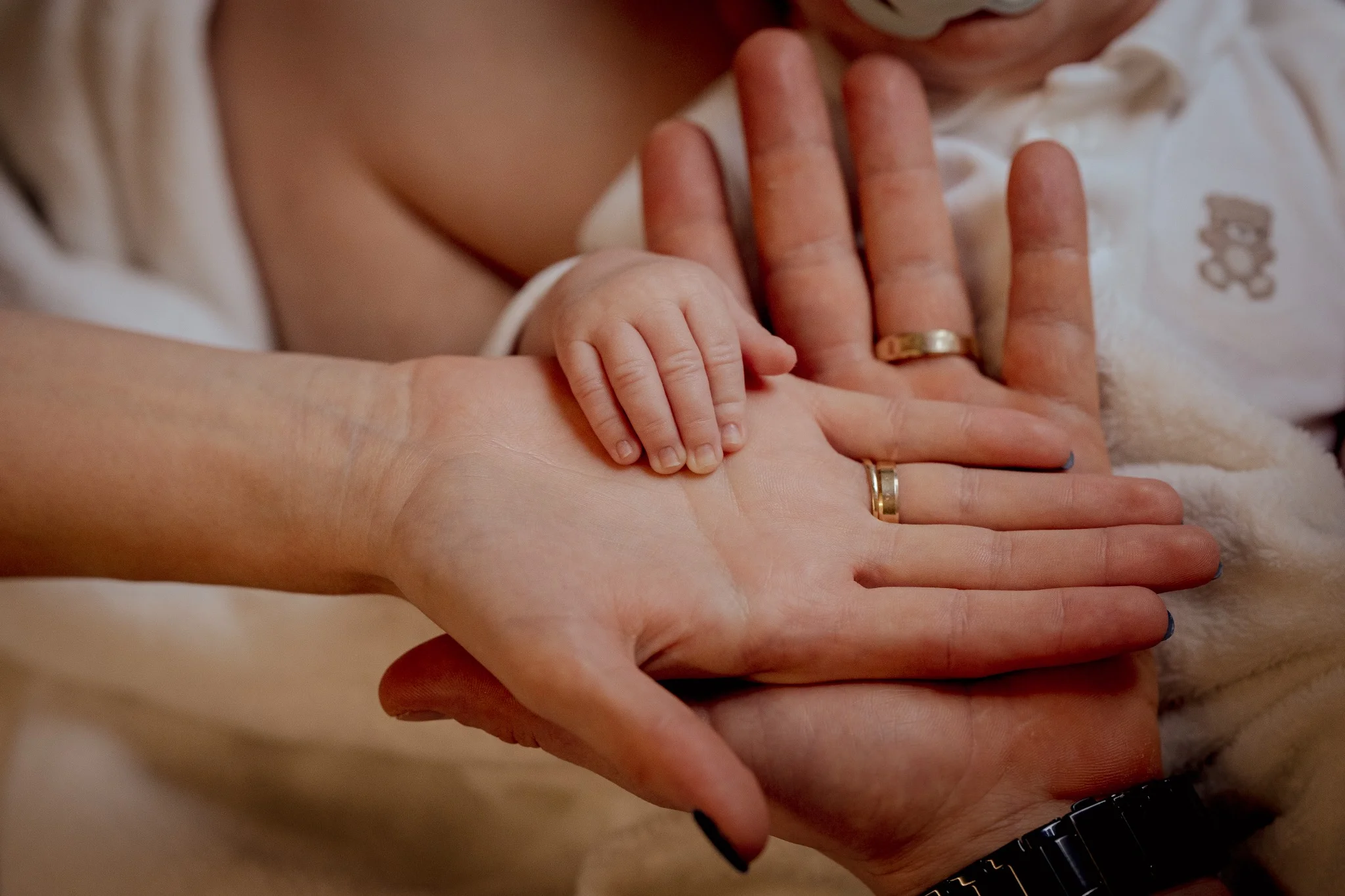  Na zdjęciu widnieje rodzina podczas pikniku na świeżym powietrzu, obok spokojnego jeziora. Składa się z mężczyzny, kobiety i małego dziecka. Mężczyzna ma na sobie jasnoniebieską koszulę i krótkie spodenki, siedzi z przodu i trzyma dziecko na kolanach. Kobieta, ubrana w kolorową sukienkę i kapelusz, siedzi obok i uśmiecha się, patrząc na dziecko. Sceneria jest zielona, z dużą ilością trawy i drzew w tle. Całość tworzy spokojną i sielankową atmosferę.