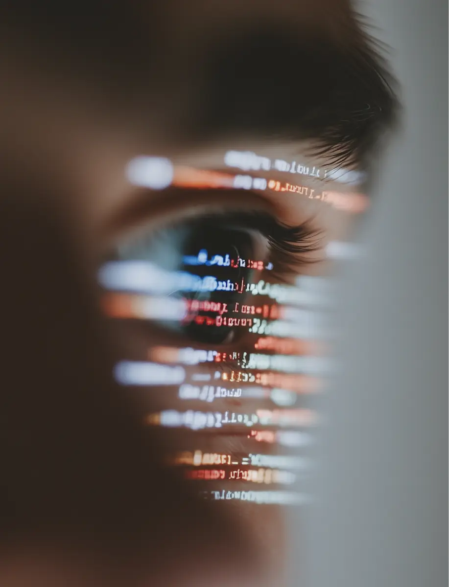 Close-up of a human eye with blurred lines of computer code reflected across the face, creating a futuristic technology-themed effect.