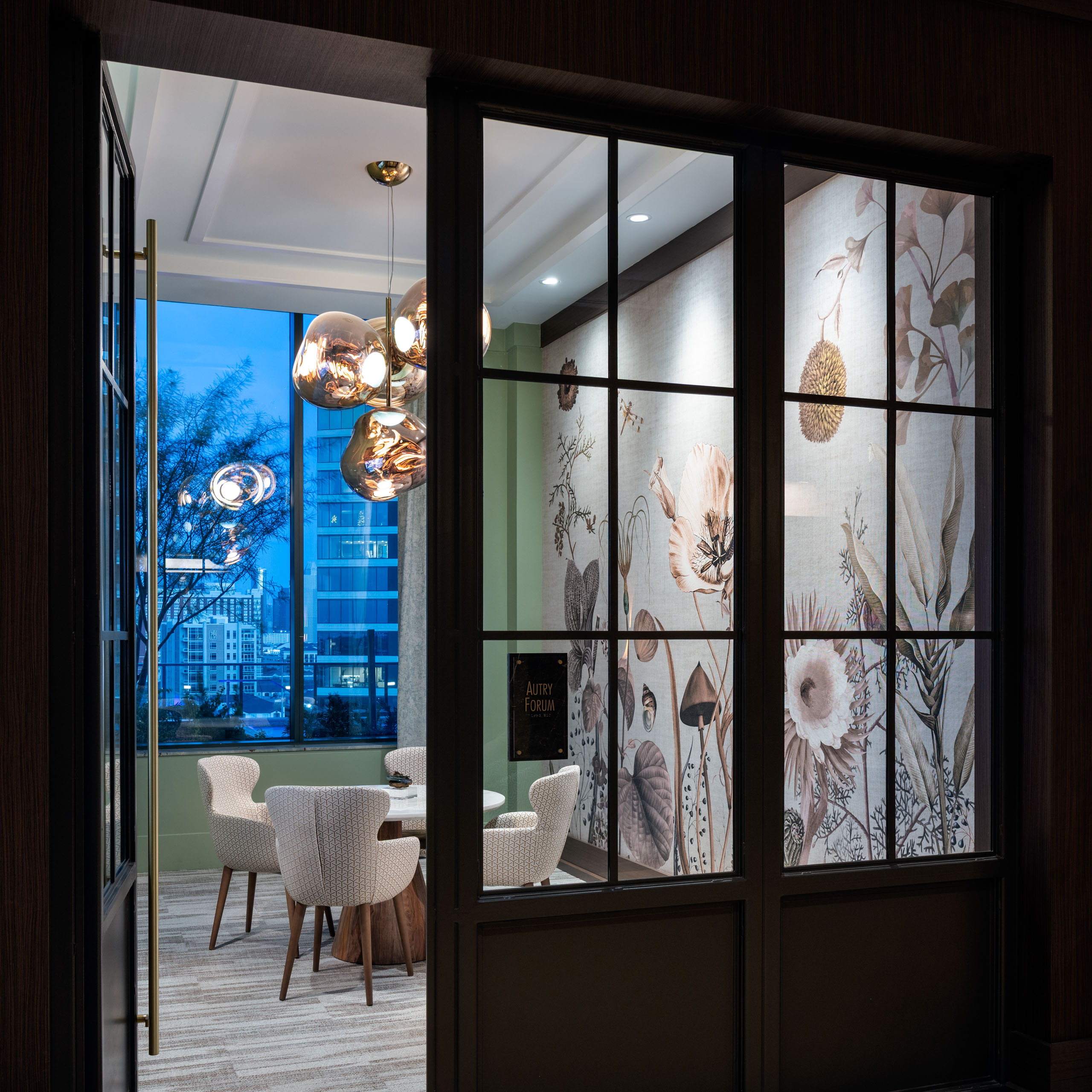 Modern meeting room with floral wallpaper and city view.