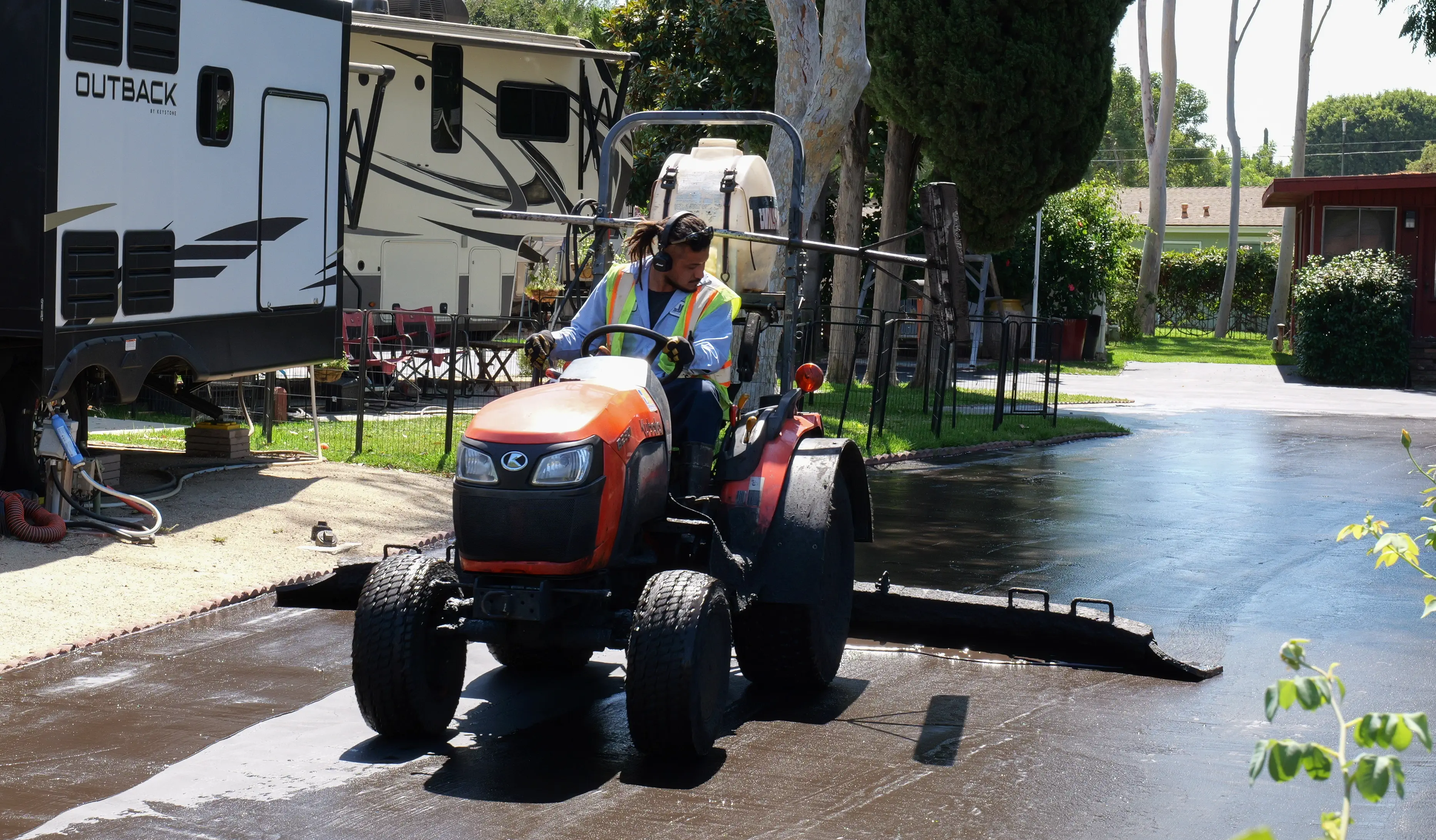 Man operating squeegee tractor on seal coating project