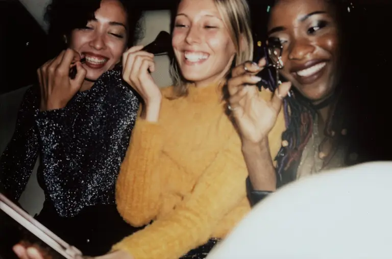 Three friends laughing together at a party.