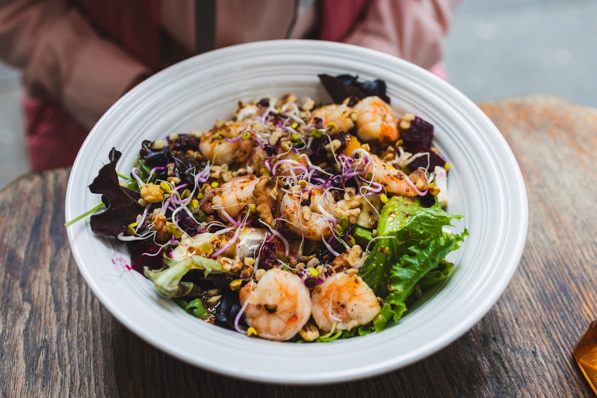 A bowl of leafy greens and whole grains topped with seafood, foods rich in omega-3s and magnesium