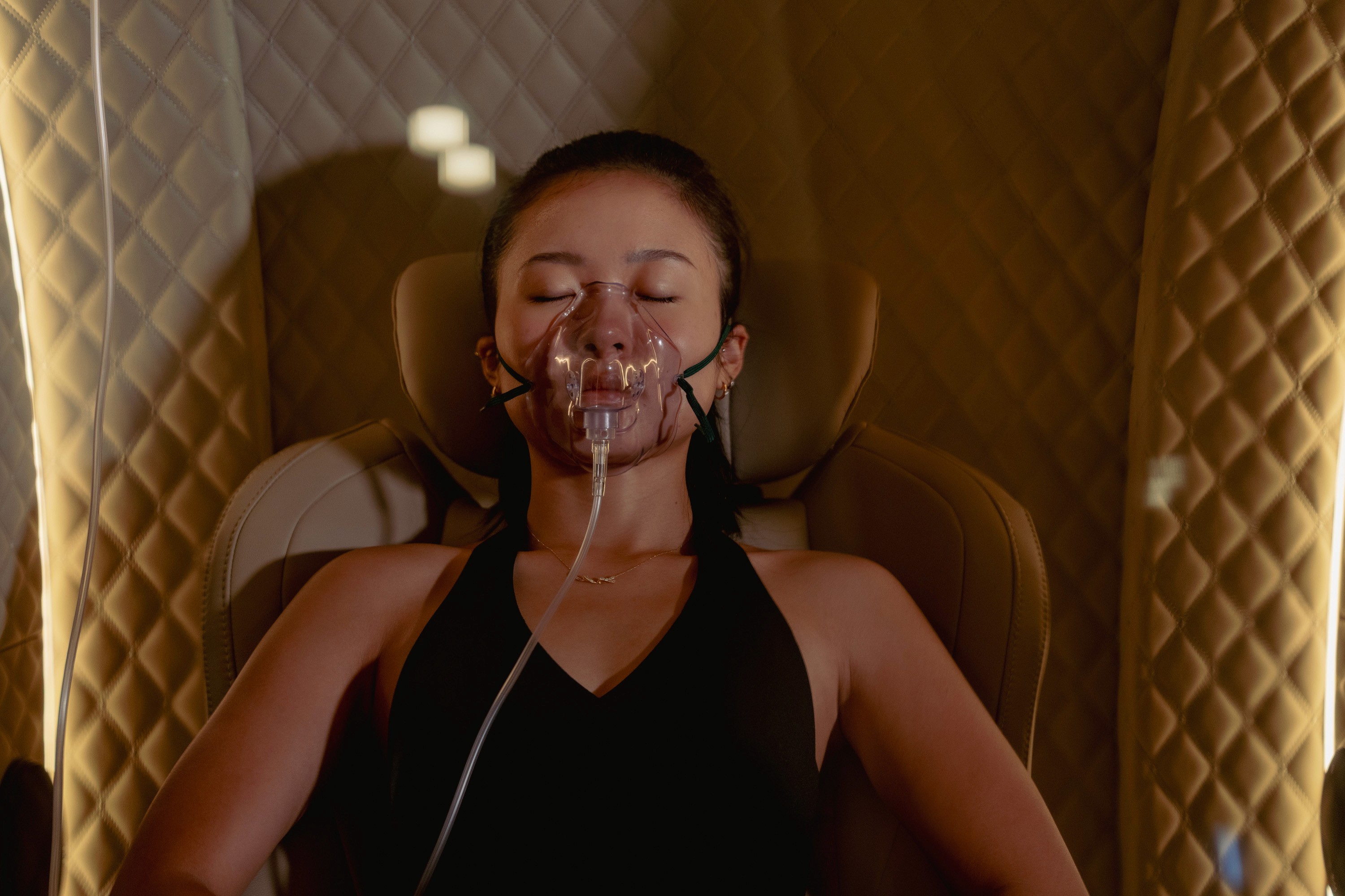 A person in a dark, serene environment is illuminated by soft lighting, exuding a sense of calm and focus, embodying the essence of premium fitness, spa, and wellness retreats.