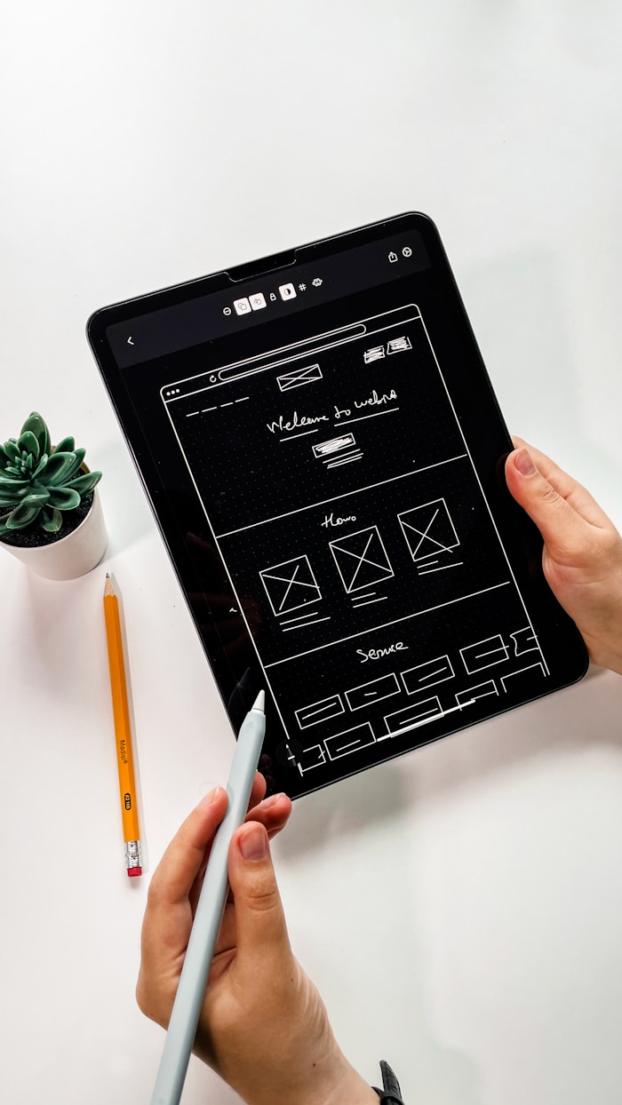 Hand-drawn website layout wireframe with hero and sections on a tablet