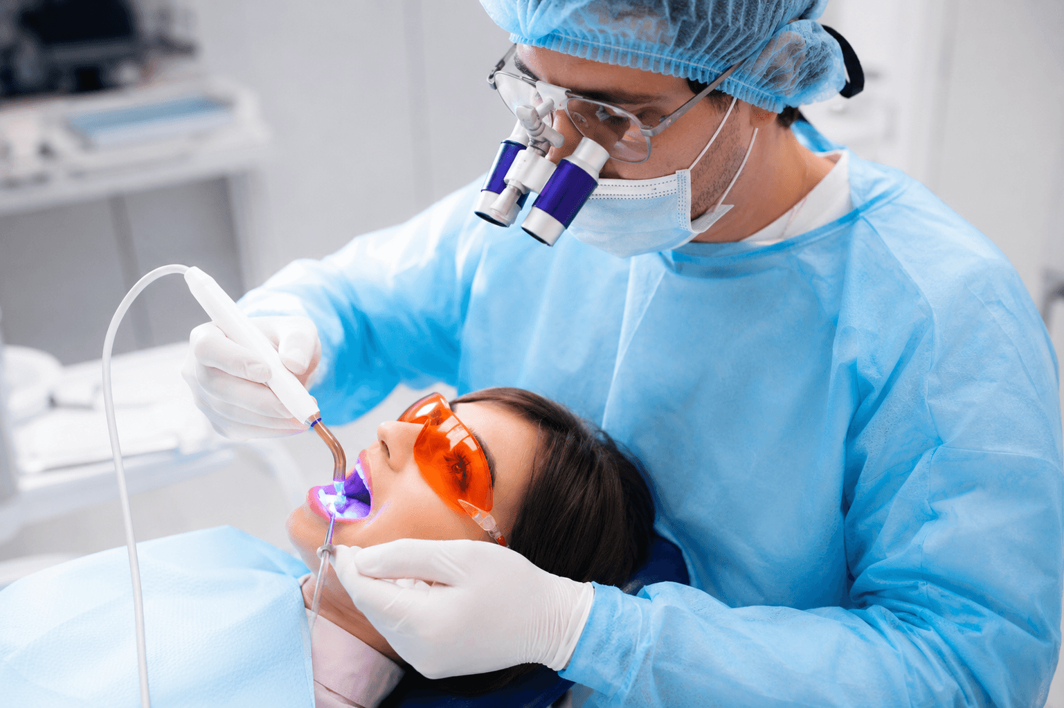 Dentist performing laser dentistry procedure on patient wearing protective orange eyewear in Dubai clinic. 
