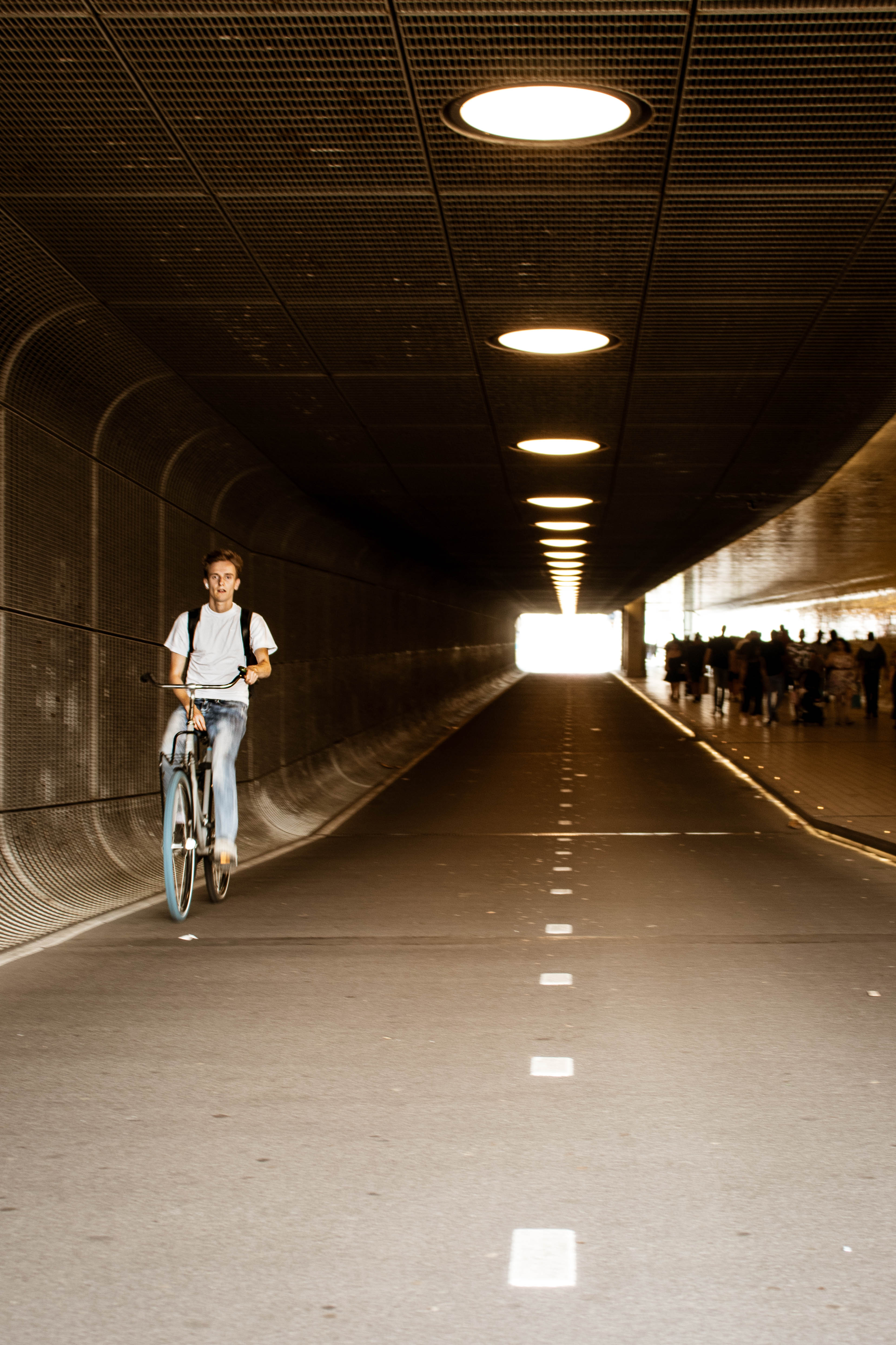 Person riding a bicycle through an urban tunnel toward daylight, symbolizing movement and navigating life’s path.