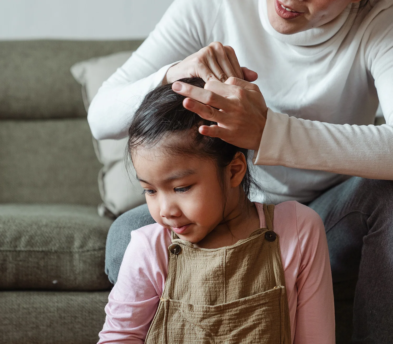 A young girl getting her hair tied up for head lice removal treatment