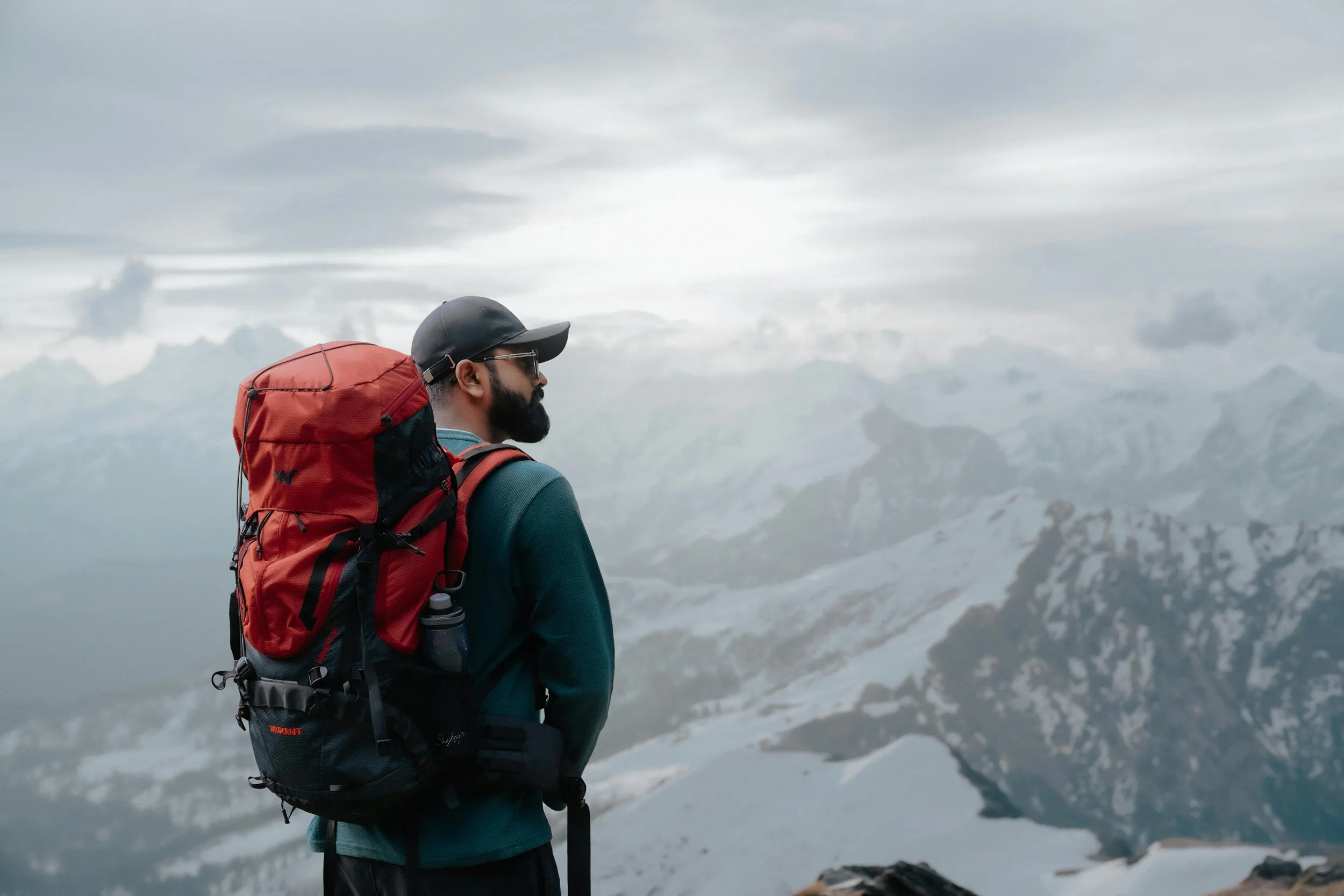 Male hiker with red backpack overlooking mountain valley, travel photography and hiking adventure