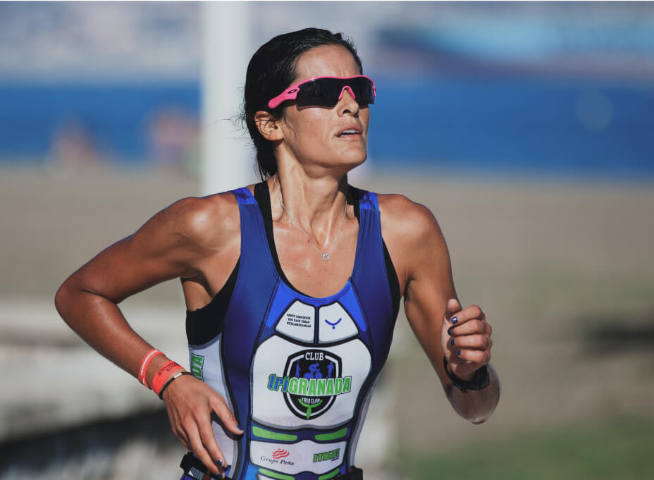 A female visa to greencard track runner with pink sunglasses and a blue uniform running on a racetrack in the sun