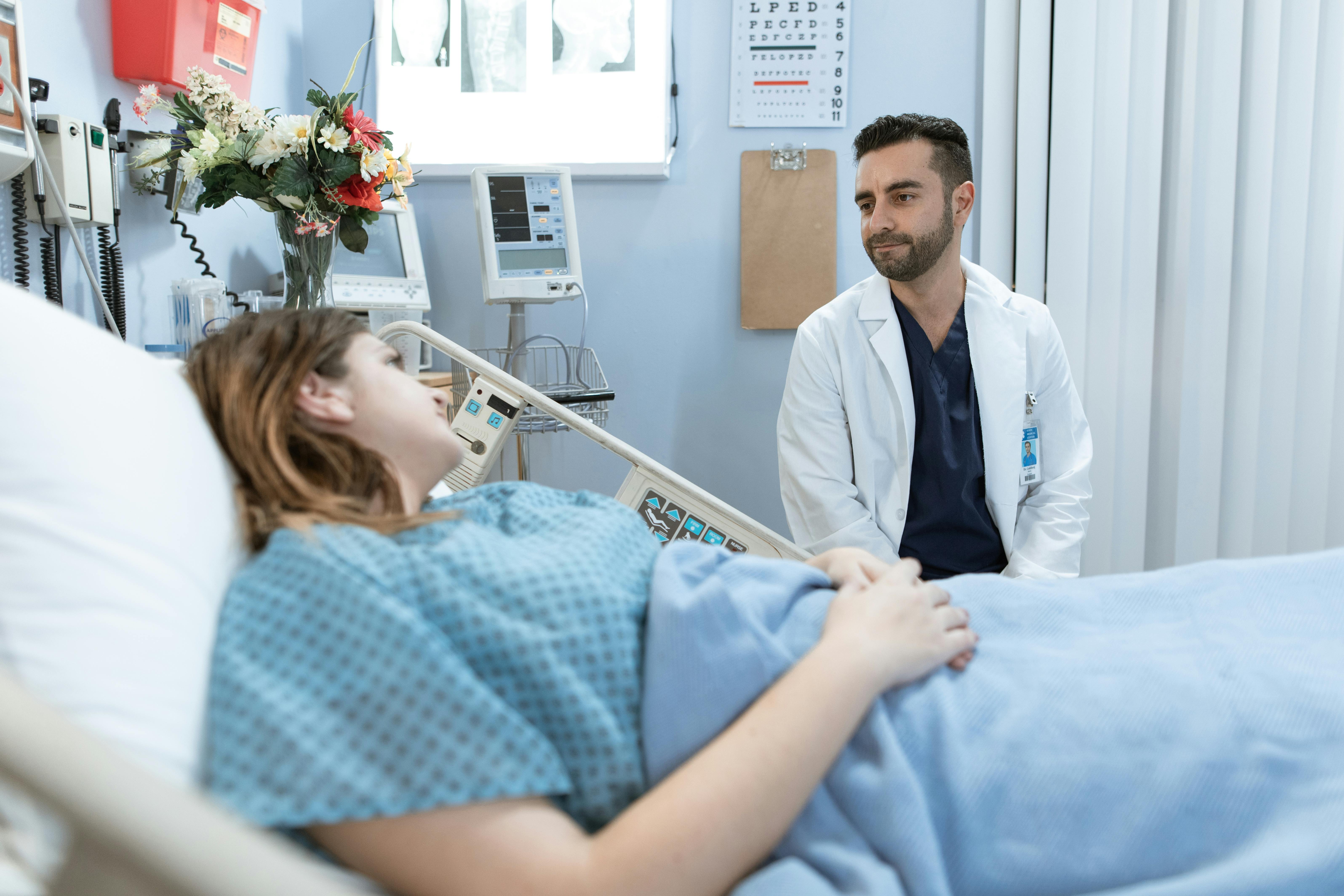 Doctor talking with a patient lying in a hospital bed during a medical consultation