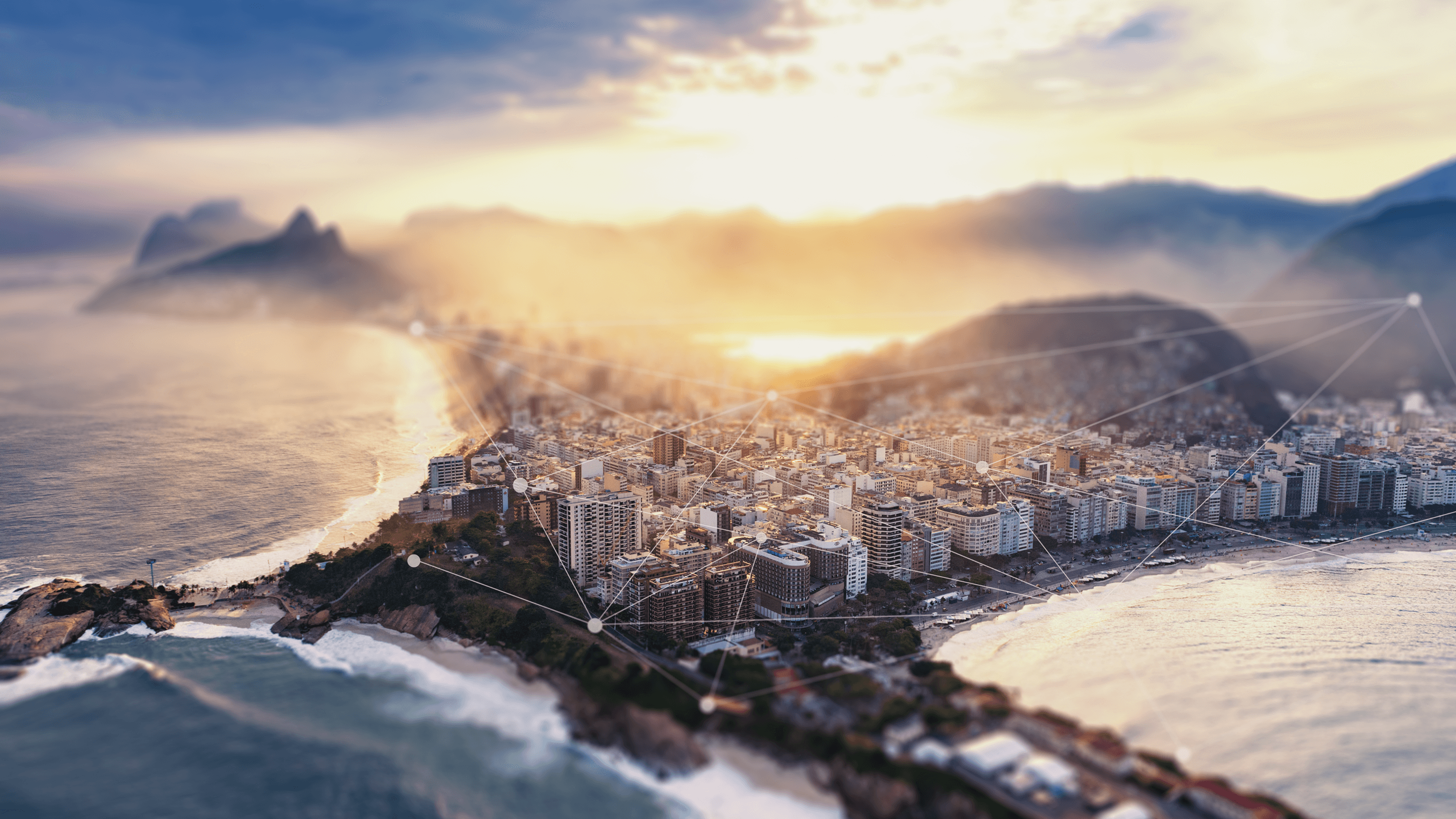 Aerial view of Rio de Janeiro’s coastline at sunset, with a network of digital connections over the buildings.