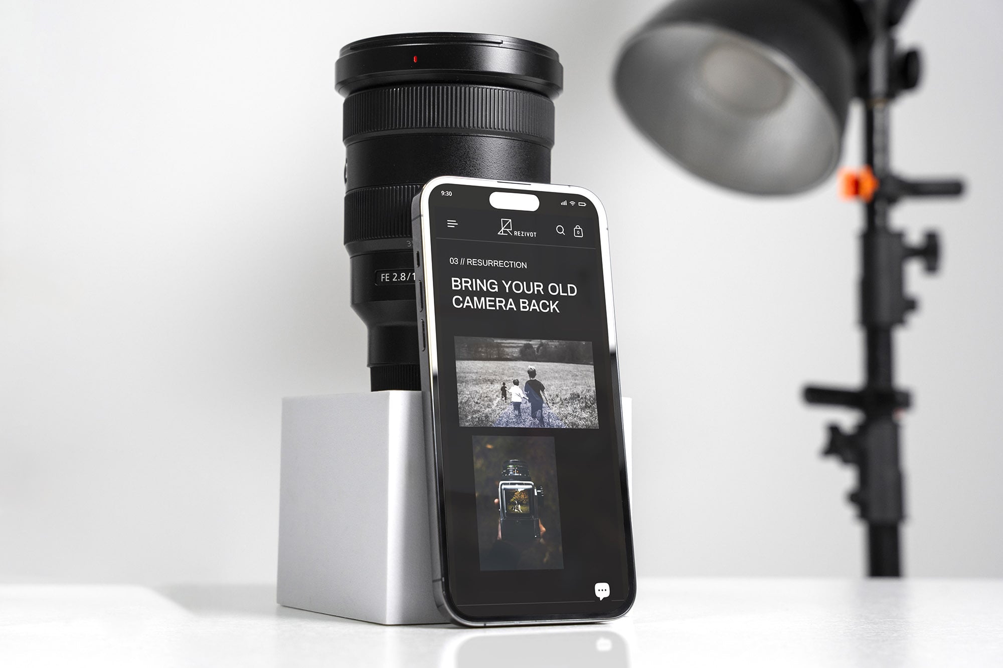 這張圖像展示了Rezivot的手機設計，頁面內顯示了「BRING YOUR OLD CAMERA BACK」的口號。手機擺放在一個相機鏡頭旁，背景是攝影燈。