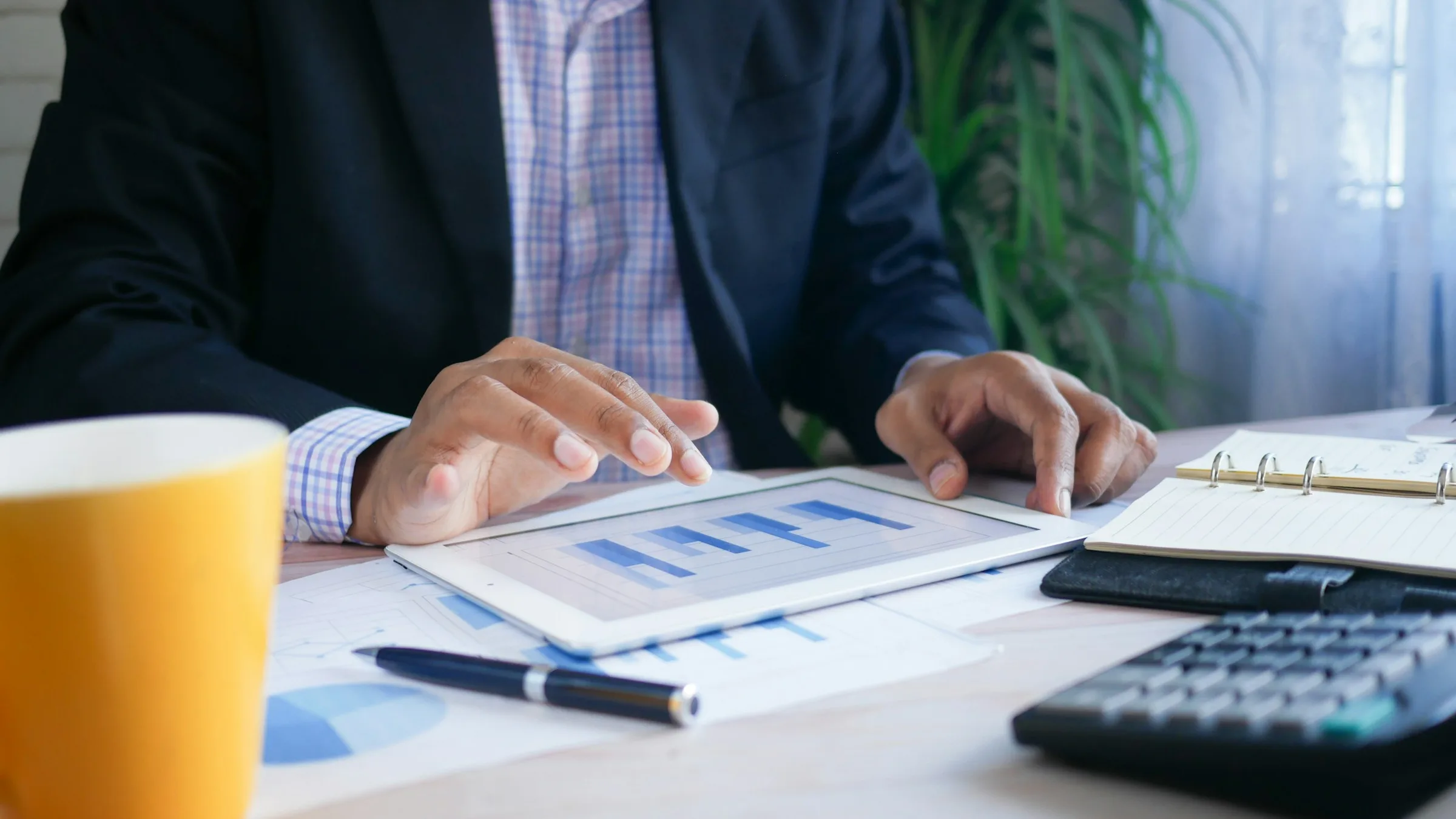 Business professional reviewing financial charts with a calculator and a coffee cup at a desk