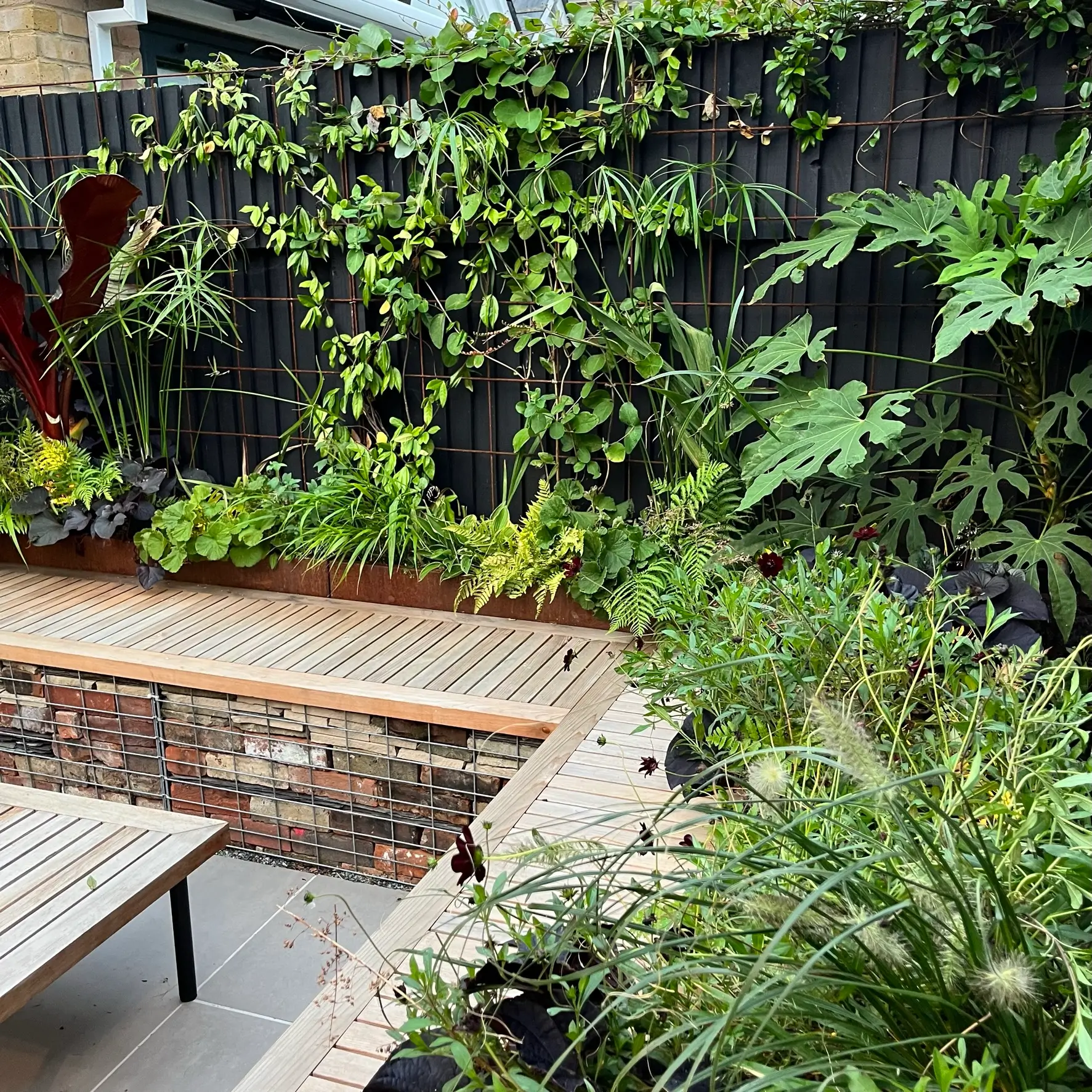 A lush garden scene featuring a wooden bench surrounded by various plants and greenery.