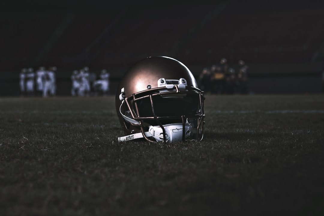 A football helmet rests on the grass, symbolizing the Miami Dolphins' Super Bowl VII victory on the field behind it.