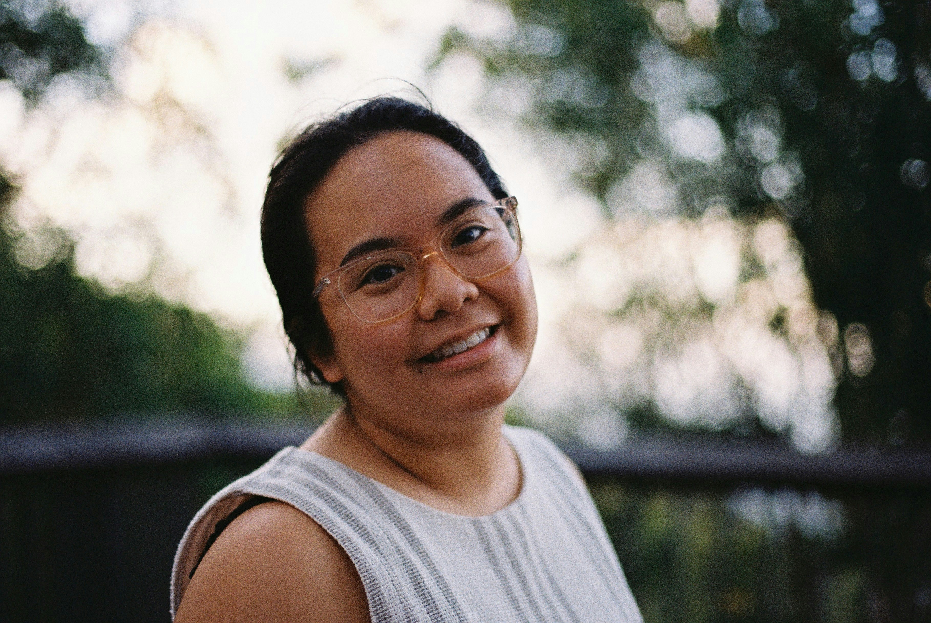 A smiling woman wearing glasses outdoors.