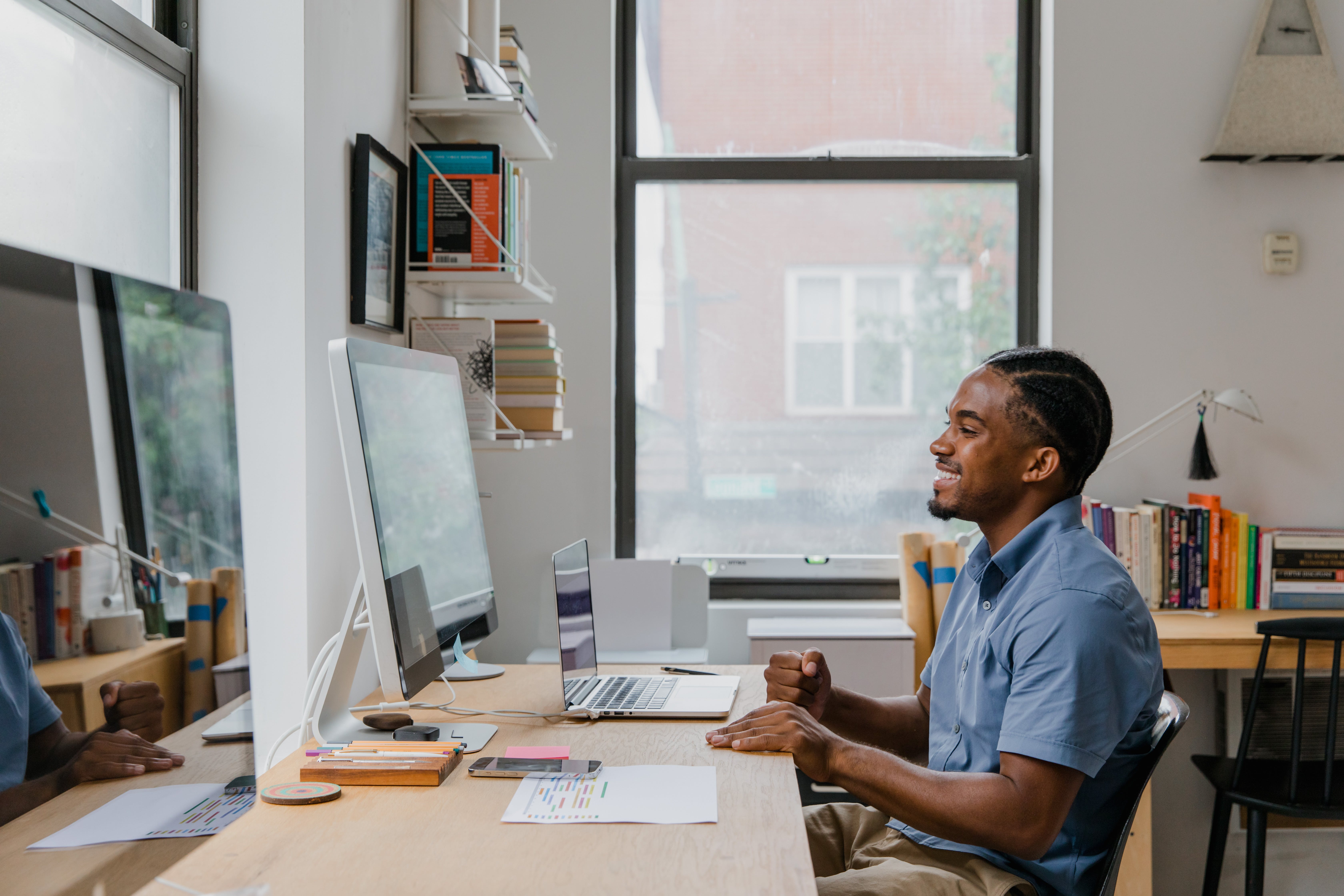 Man sitting by desk checking broker timelines using laptop and computer